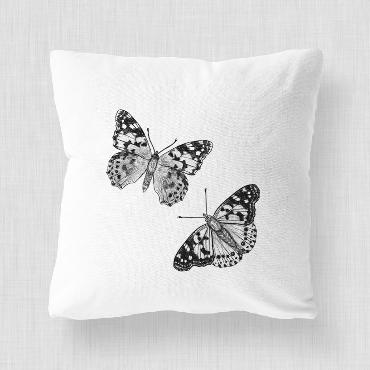 White pillow cover printed with a detailed black ink illustration of two painted lady butterflies.
