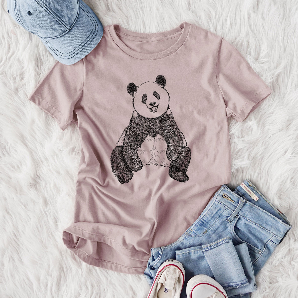 Women's relaxed fit cotton t-shirt printed with a black ink illustration of a giant panda sitting and facing forward, styled flat on a white faux fur rug with jeans.