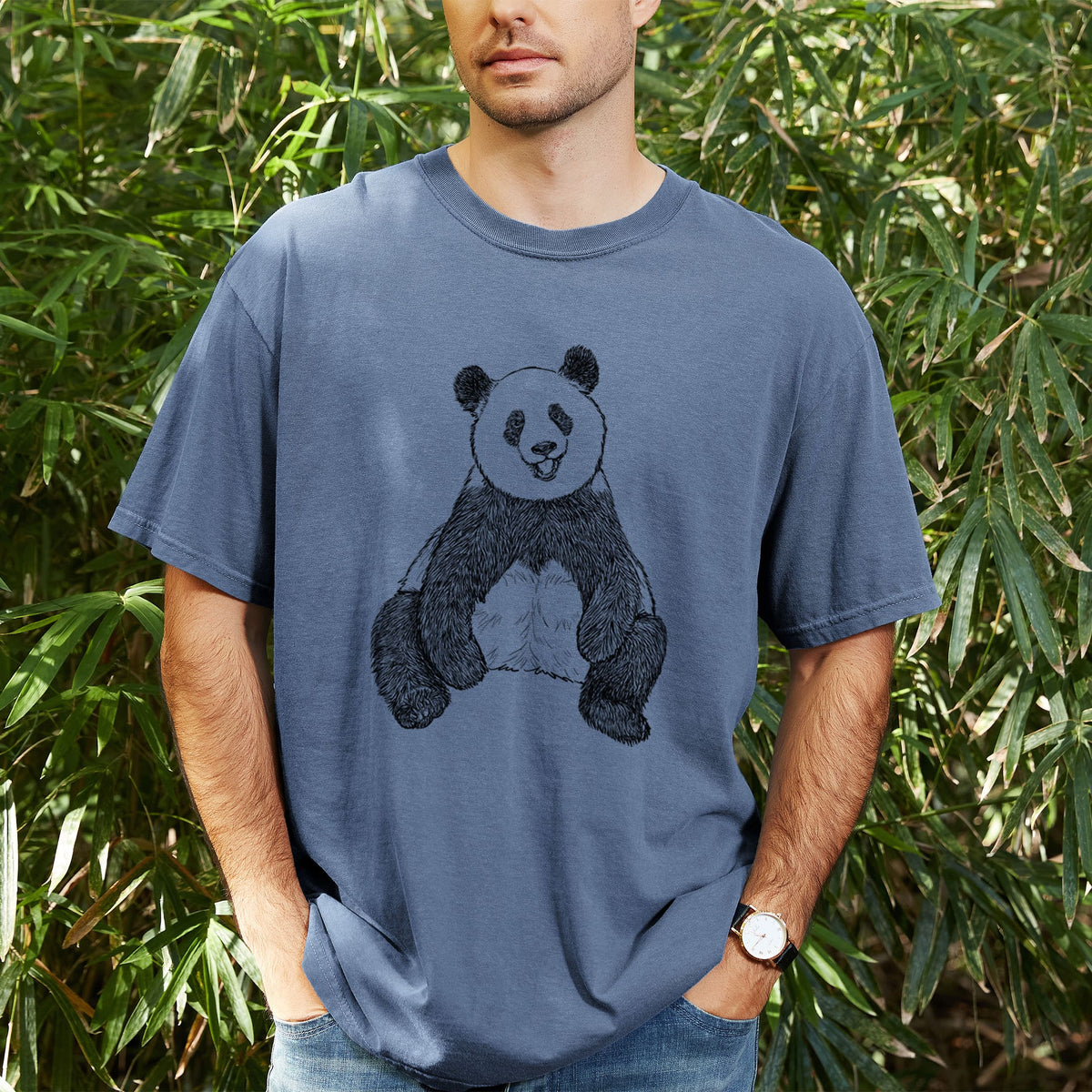Man wearing a Comfort Colors t-shirt printed with a black ink illustration of a giant panda sitting and facing forward, outdoors.