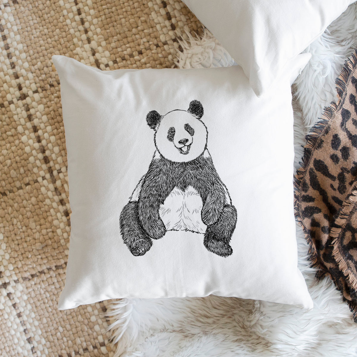 White pillow cover printed with a black ink illustration of a giant panda sitting and facing forward, on a woven chair.