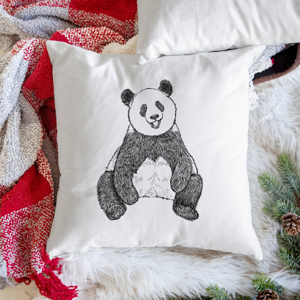 White pillow cover printed with a black ink illustration of a giant panda sitting and facing forward, on a woven chair.