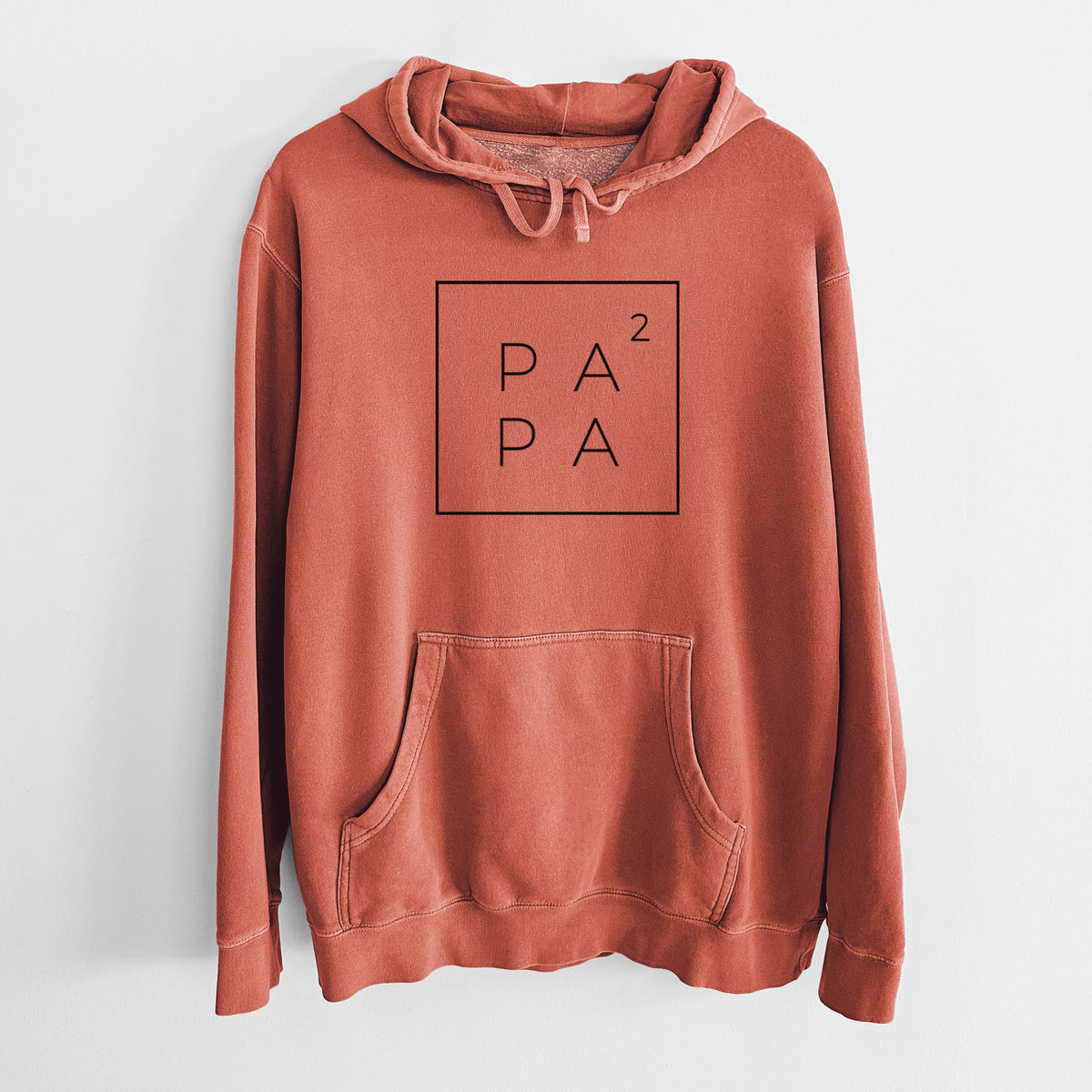 Amber orange pigment dyed hoodie laid flat, printed with the word PAPA stacked inside a square outline with a small squared symbol, for a papa of two.
