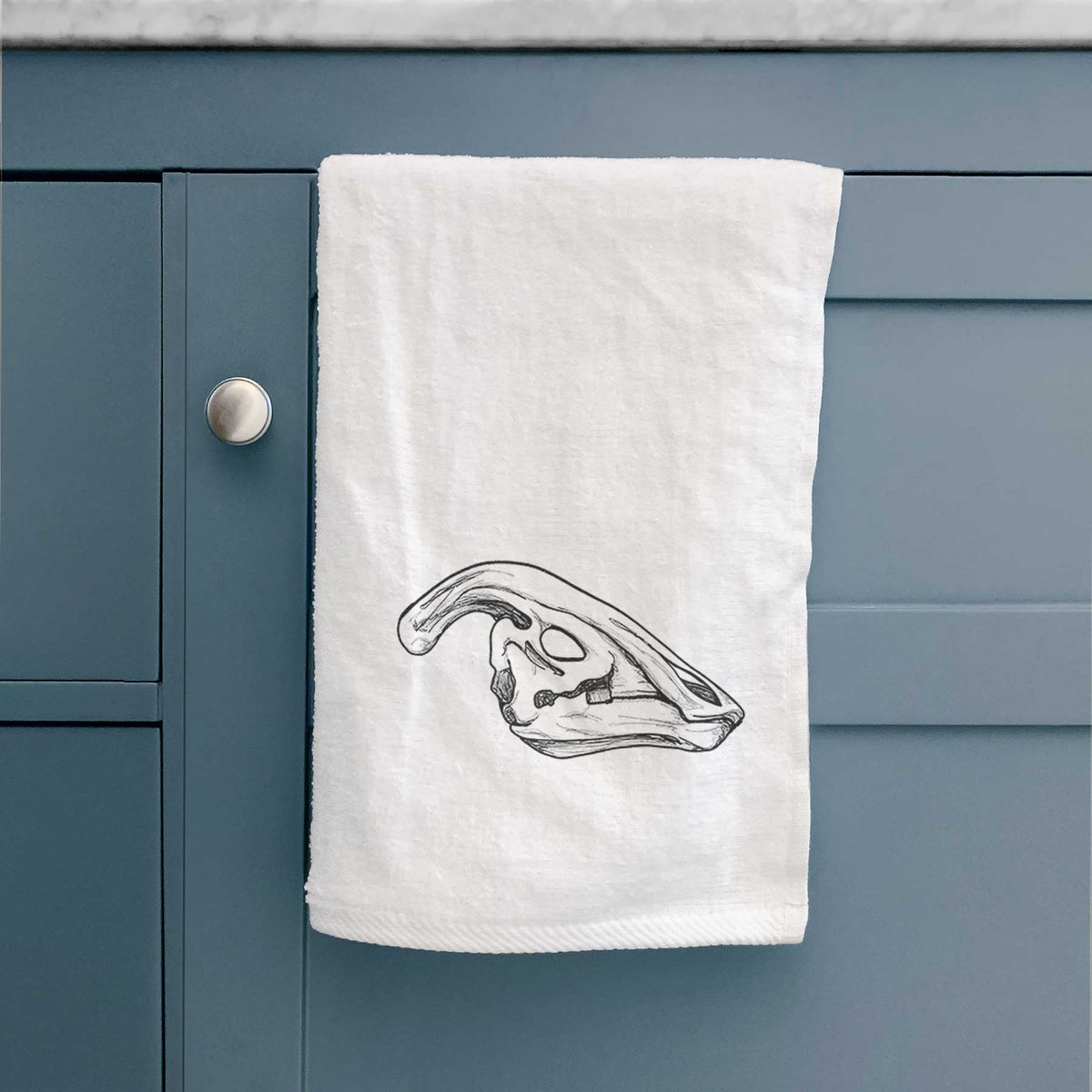 White hand towel printed with a detailed black ink illustration of a crested Parasaurolophus skull.
