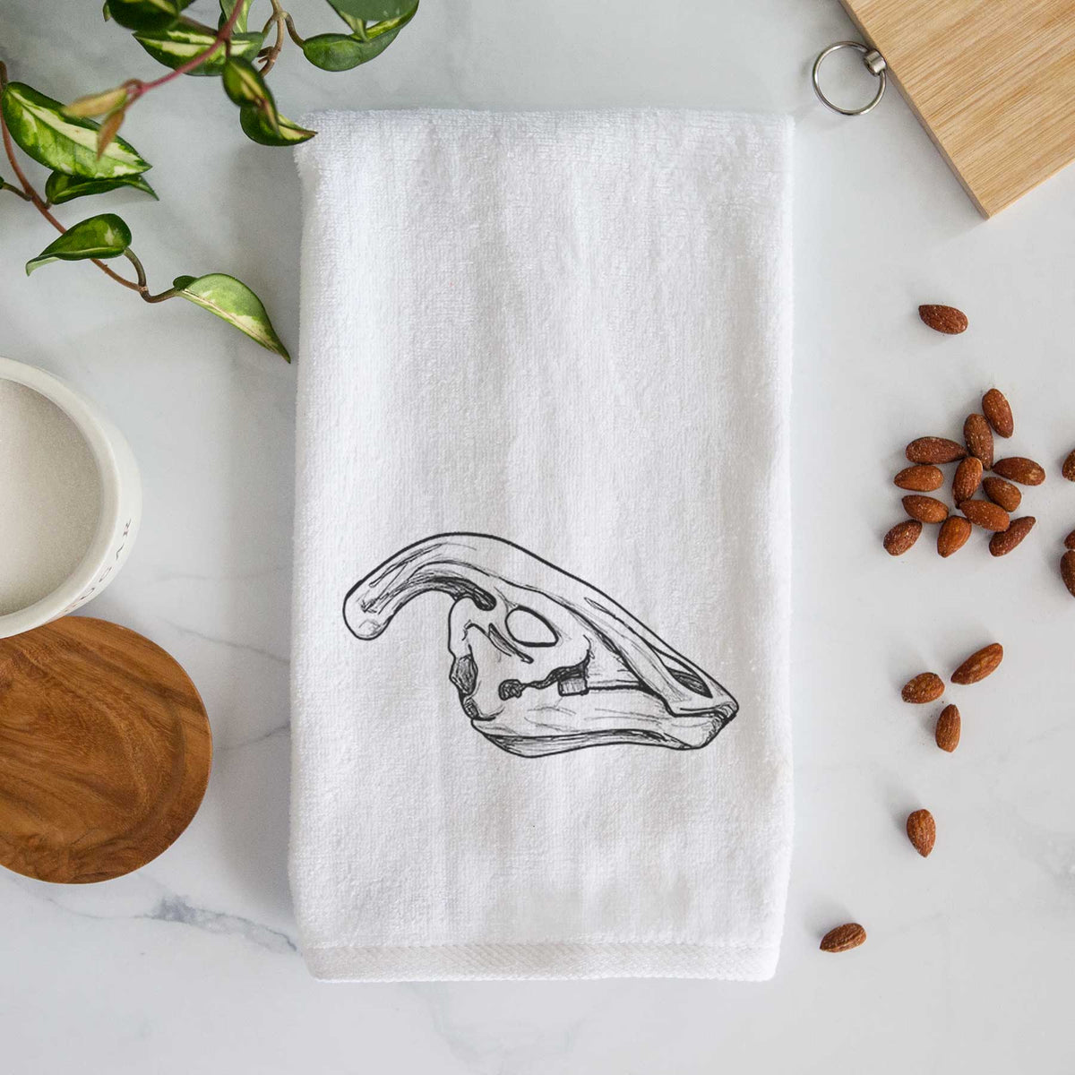 White hand towel printed with a detailed black ink illustration of a crested Parasaurolophus skull.