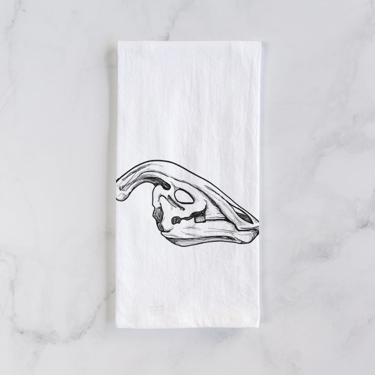 White cotton tea towel laid flat on marble, printed with a detailed black ink illustration of a crested Parasaurolophus skull.
