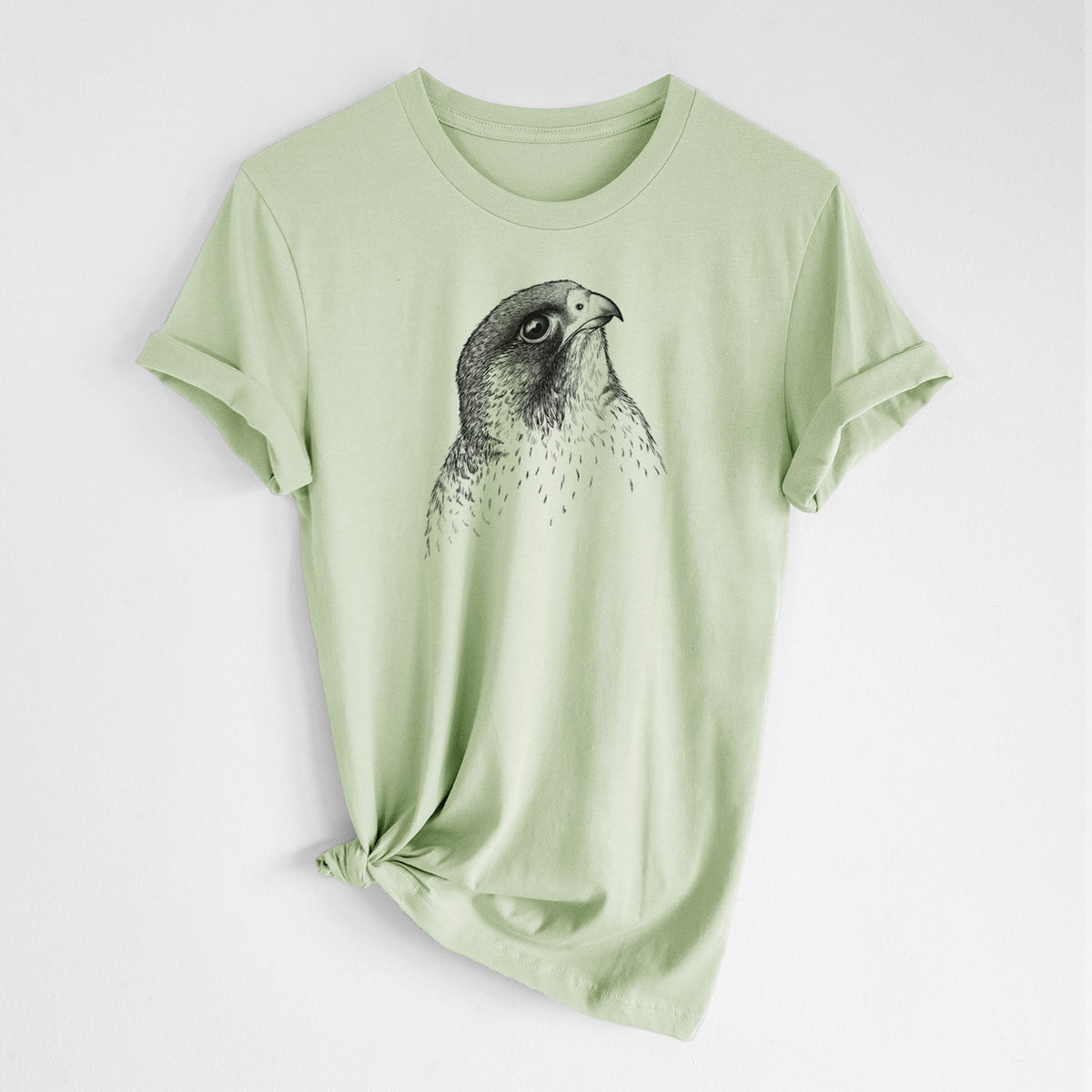 Spring green lightweight cotton t-shirt laid flat with the sleeves rolled, printed with a detailed black ink portrait of a peregrine falcon's head.