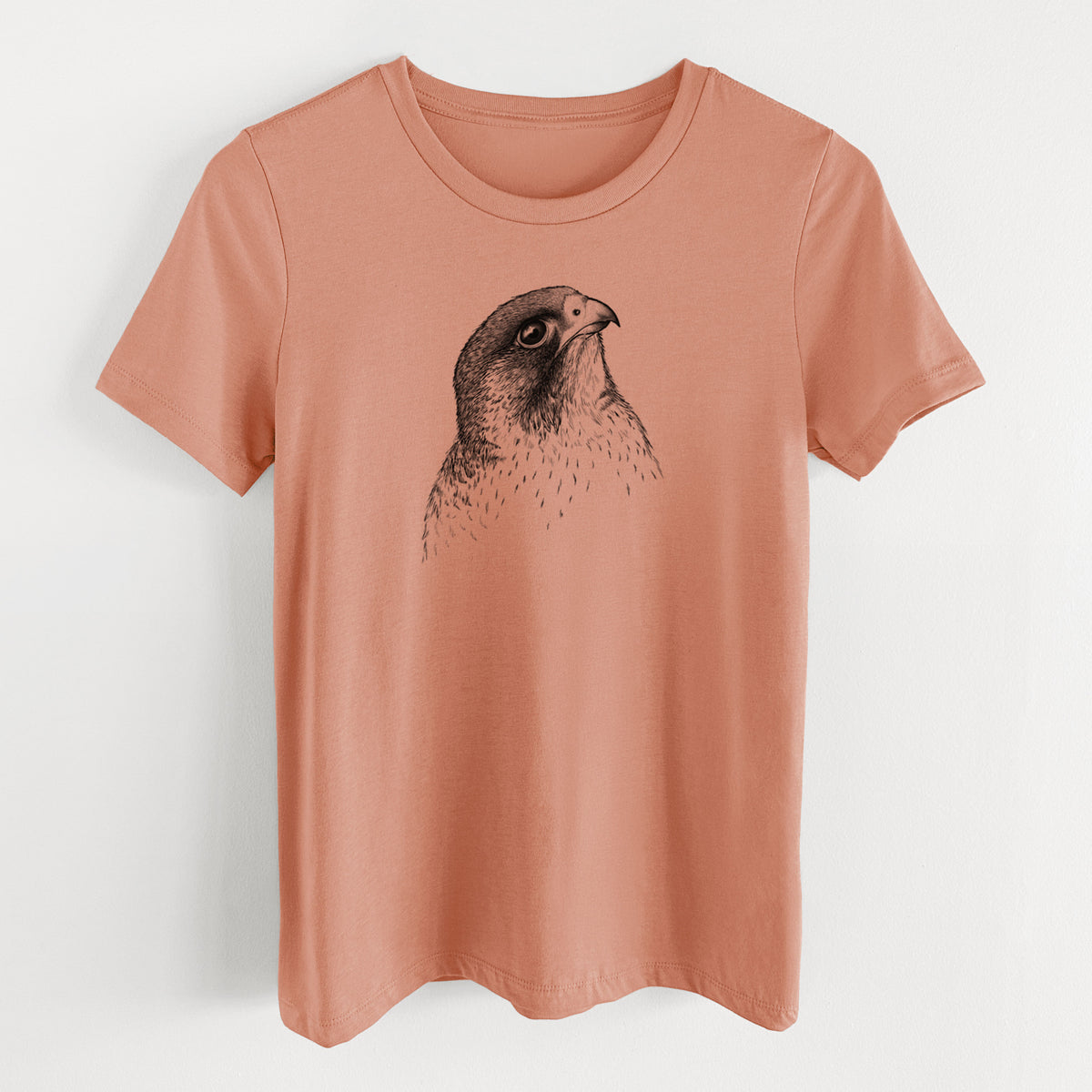Terracotta orange women's relaxed fit cotton t-shirt laid flat, printed with a detailed black ink portrait of a peregrine falcon's head.