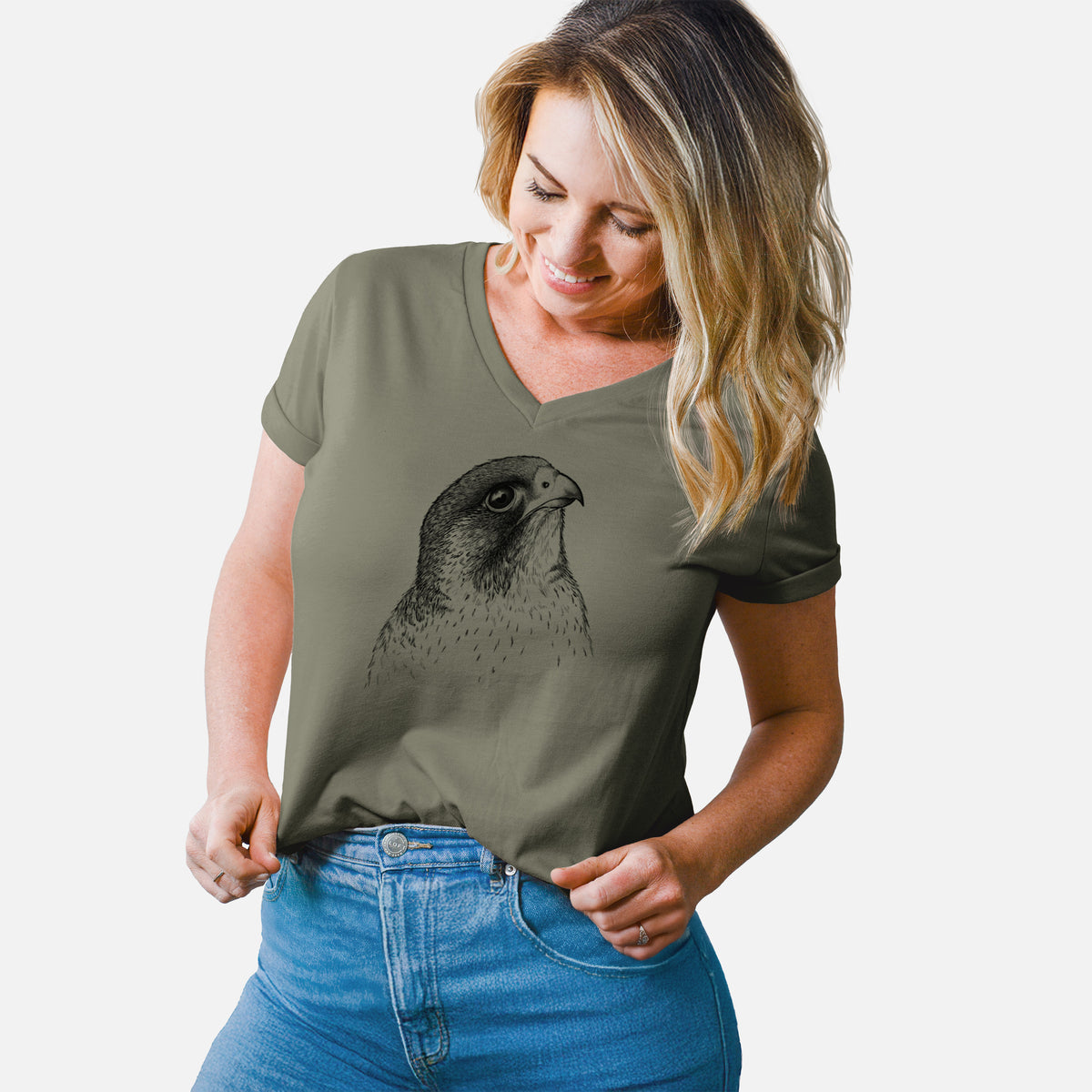 Woman wearing a military green women's relaxed fit cotton V-neck t-shirt printed with a detailed black ink portrait of a peregrine falcon's head.