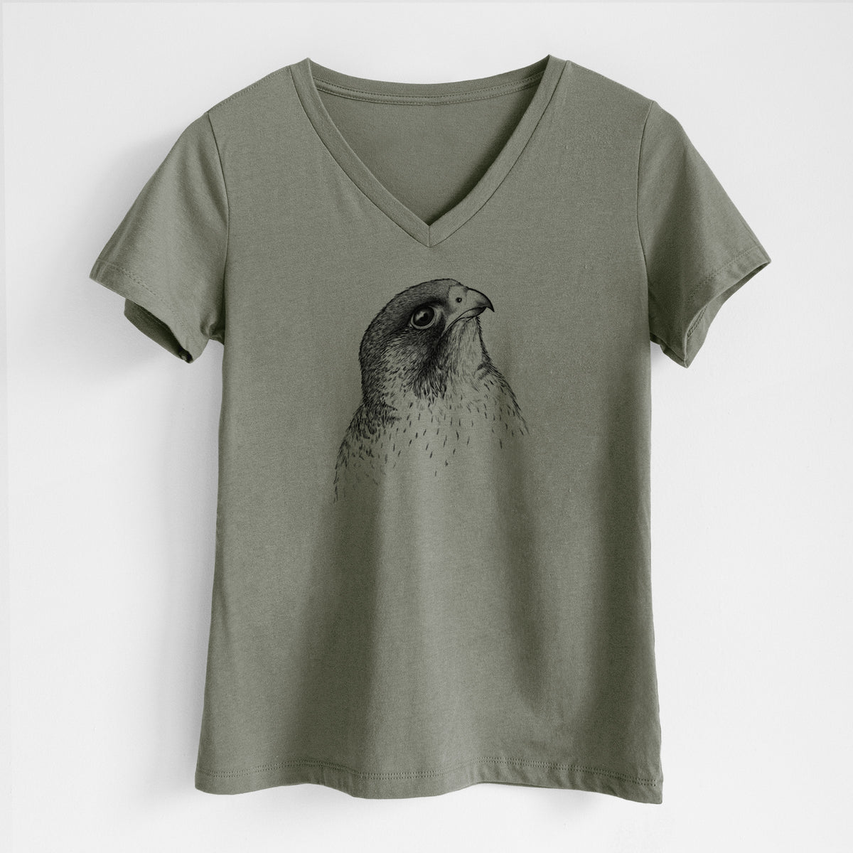 Military green women's relaxed fit cotton V-neck t-shirt laid flat, printed with a detailed black ink portrait of a peregrine falcon's head.