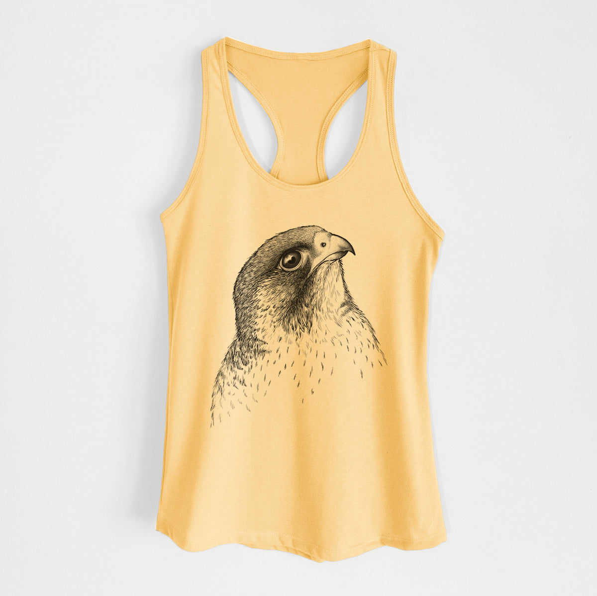 Banana cream women's racerback tank top laid flat, printed with a detailed black ink portrait of a peregrine falcon's head.