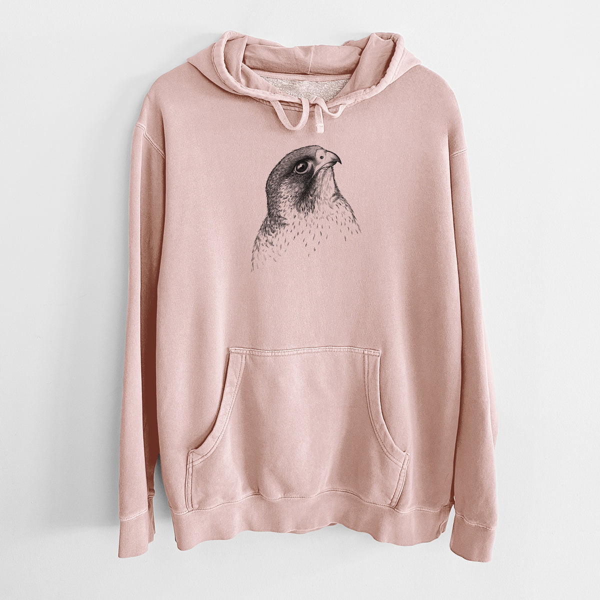 Dusty pink pigment dyed hoodie laid flat, printed with a detailed black ink portrait of a peregrine falcon's head.