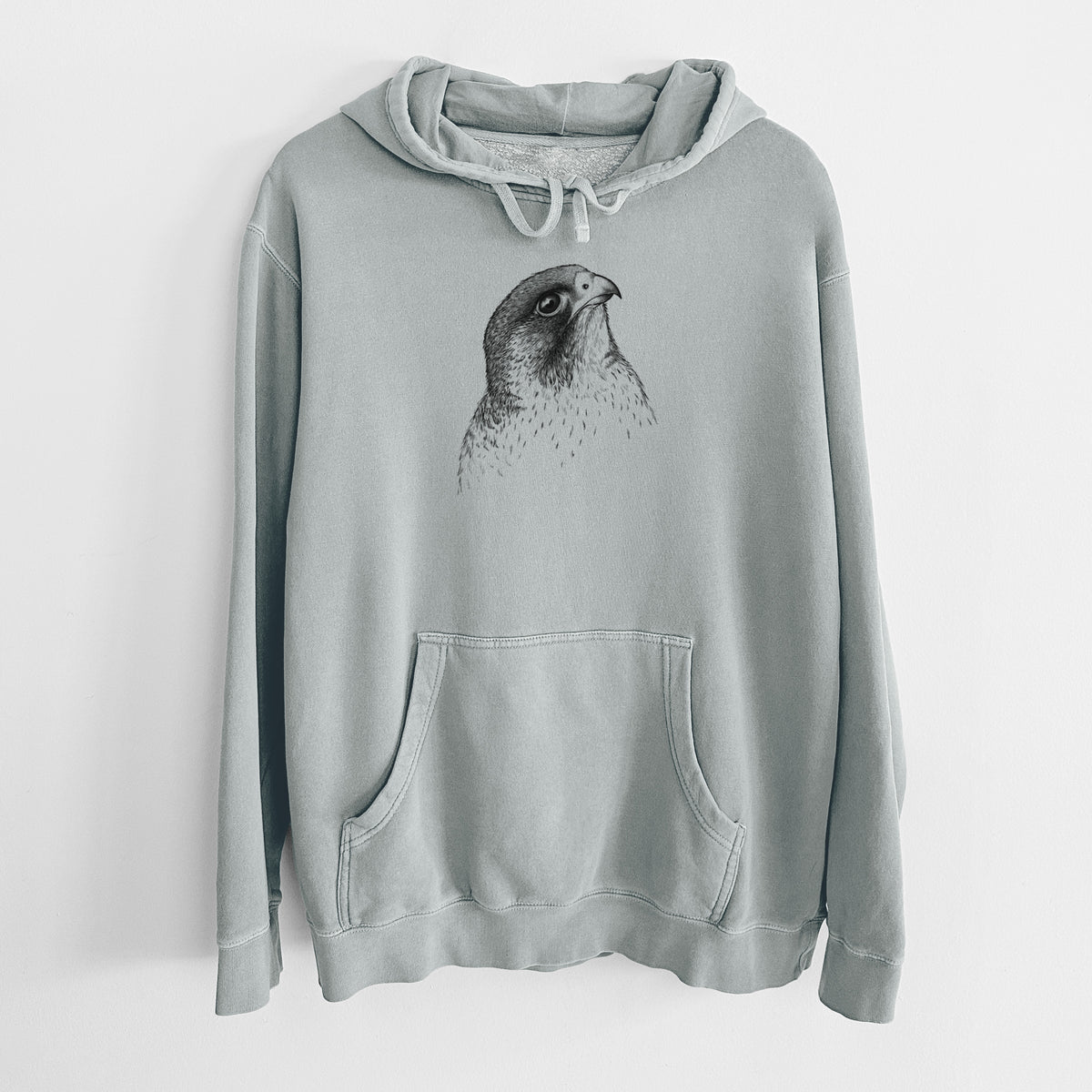 Sage green pigment dyed hoodie laid flat, printed with a detailed black ink portrait of a peregrine falcon's head.