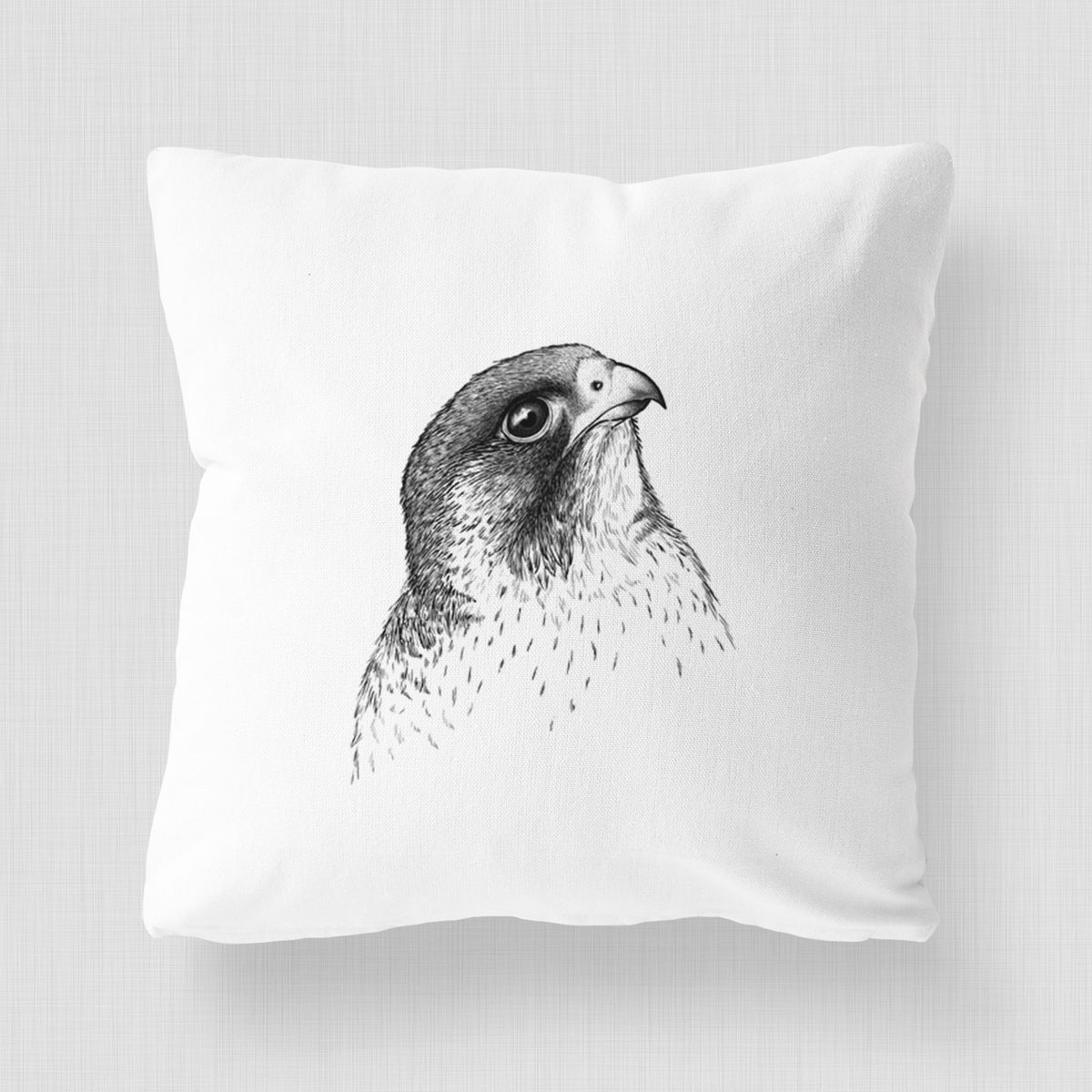White pillow cover printed with a detailed black ink portrait of a peregrine falcon's head.