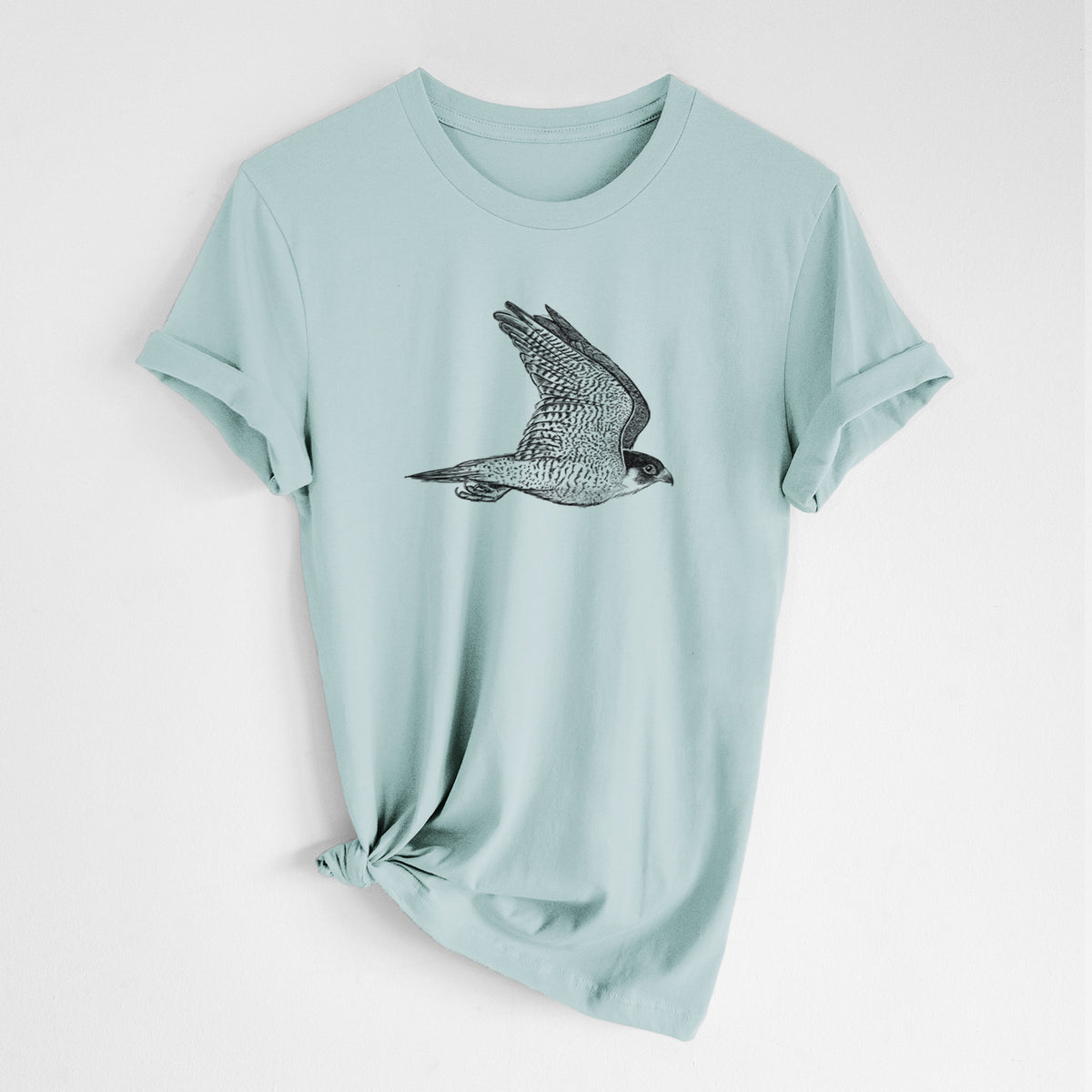 Dusty blue lightweight cotton t-shirt laid flat with the sleeves rolled, printed with a detailed black ink illustration of a peregrine falcon in flight.