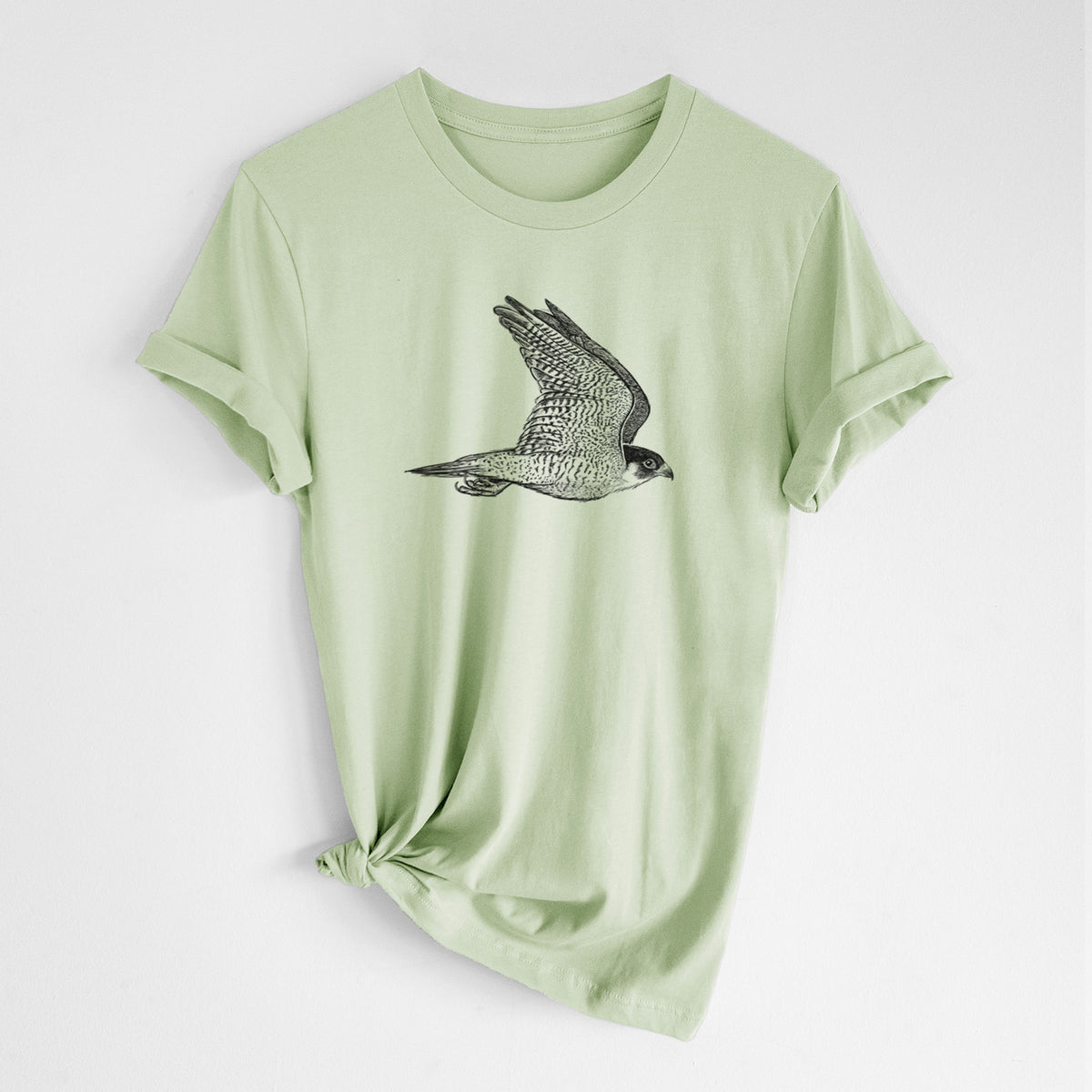 Spring green lightweight cotton t-shirt laid flat with the sleeves rolled, printed with a detailed black ink illustration of a peregrine falcon in flight.