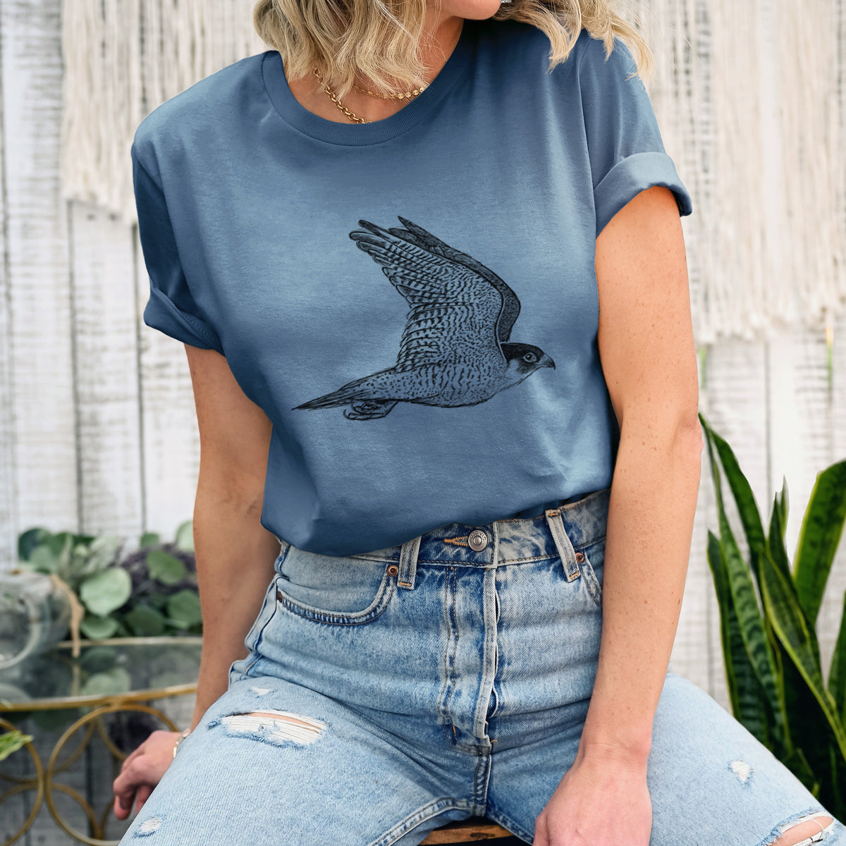 Woman wearing a steel blue lightweight cotton t-shirt printed with a detailed black ink illustration of a peregrine falcon in flight.