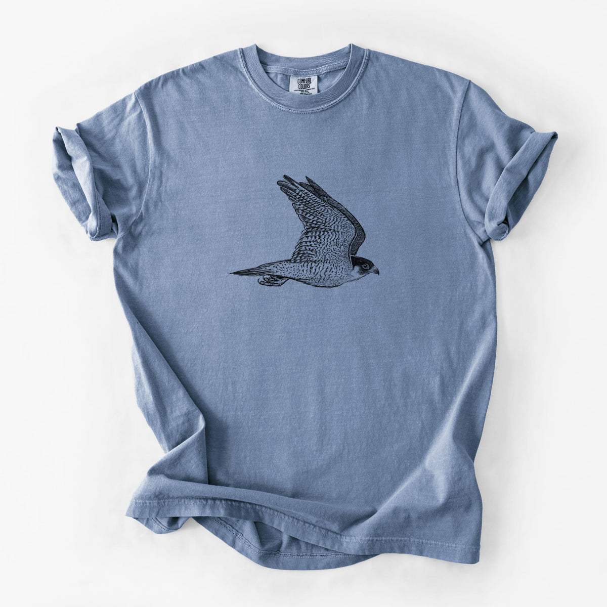 Blue jean Comfort Colors t-shirt laid flat, printed with a detailed black ink illustration of a peregrine falcon in flight.