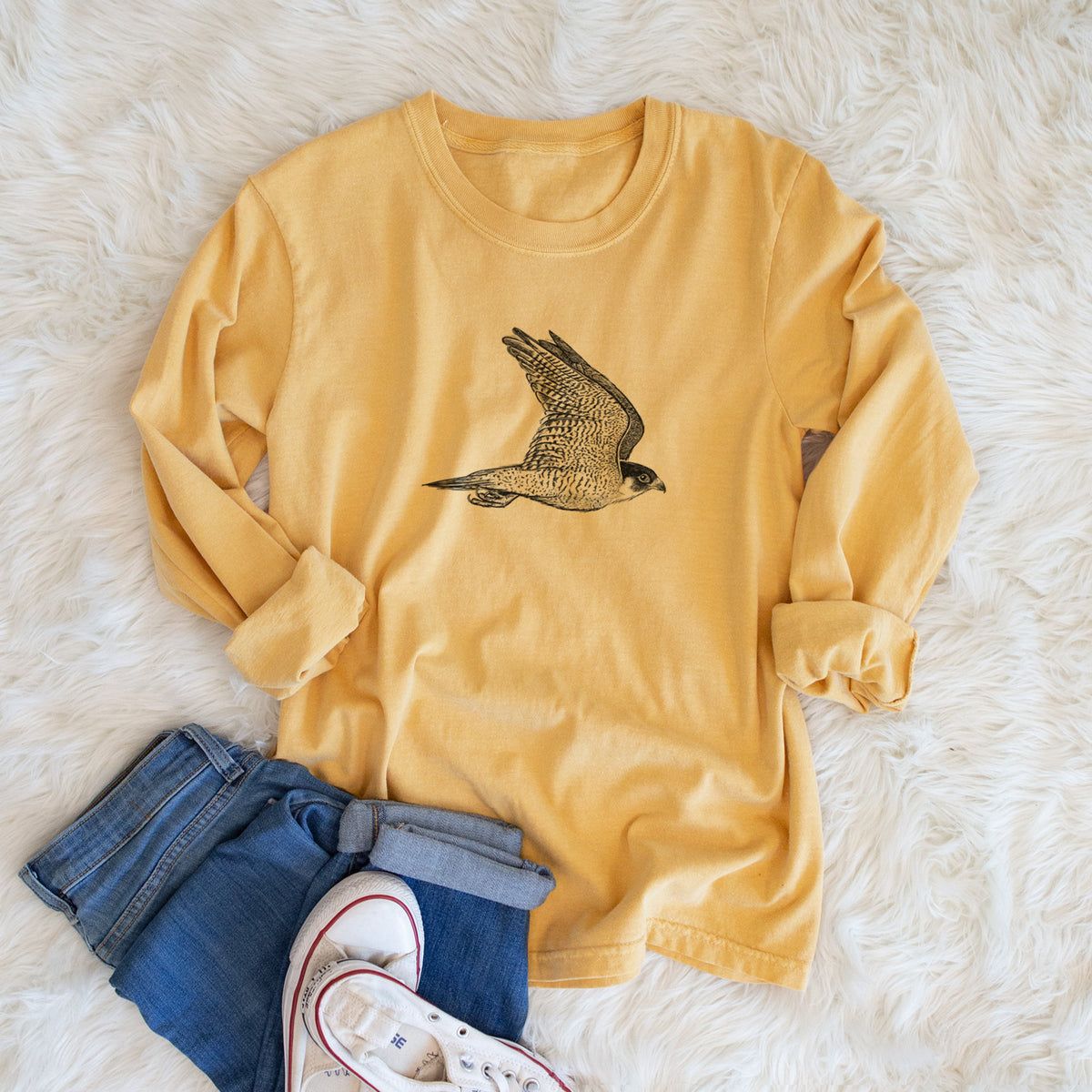 Golden wheat yellow Comfort Colors long sleeve shirt printed with a detailed black ink illustration of a peregrine falcon in flight, shown in a lifestyle photo.