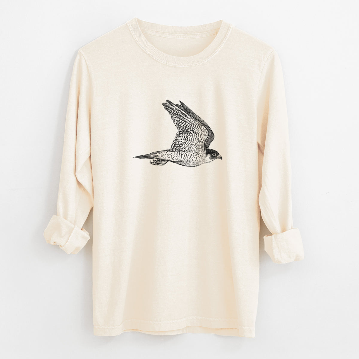 Ivory Comfort Colors long sleeve shirt laid flat with the cuffs rolled, printed with a detailed black ink illustration of a peregrine falcon in flight.