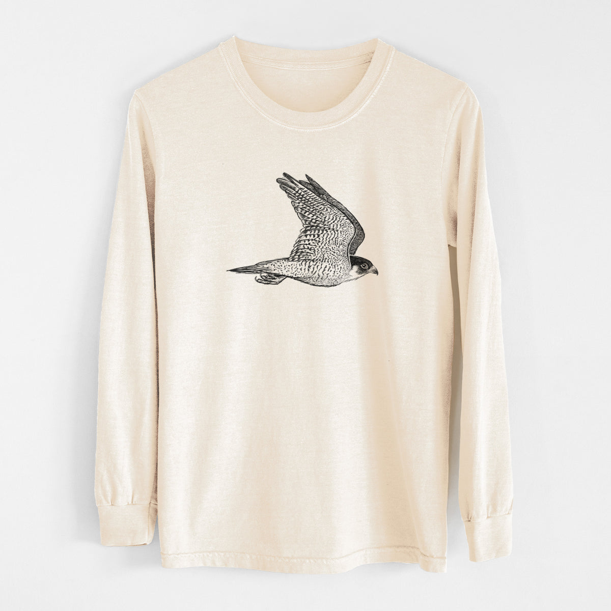 Ivory Comfort Colors long sleeve shirt laid flat, printed with a detailed black ink illustration of a peregrine falcon in flight.