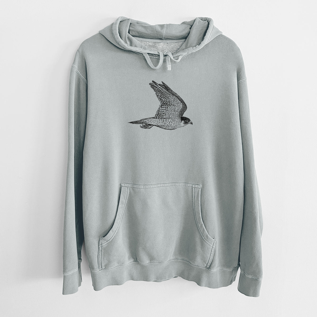 Sage green pigment dyed hoodie laid flat, printed with a detailed black ink illustration of a peregrine falcon in flight.