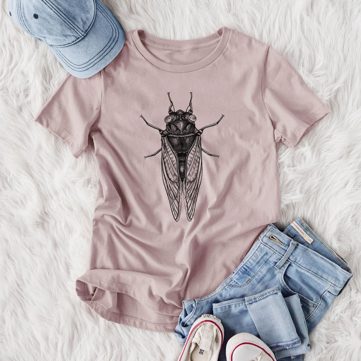 Women's relaxed fit cotton t-shirt printed with a detailed black ink illustration of a periodical cicada with its wings folded, seen from above, styled flat on a white faux fur rug with jeans.
