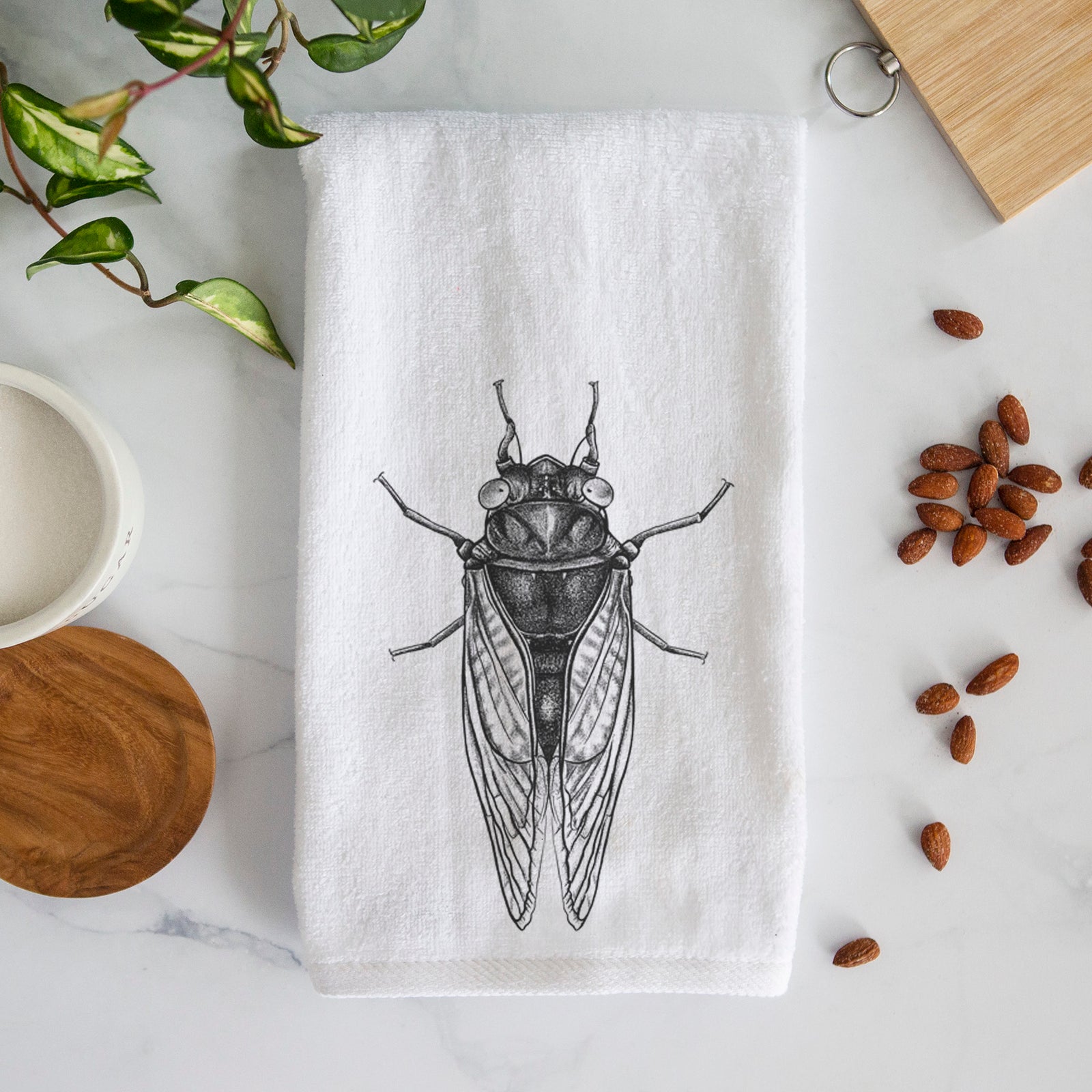 White hand towel printed with a detailed black ink illustration of a periodical cicada with its wings folded, seen from above.