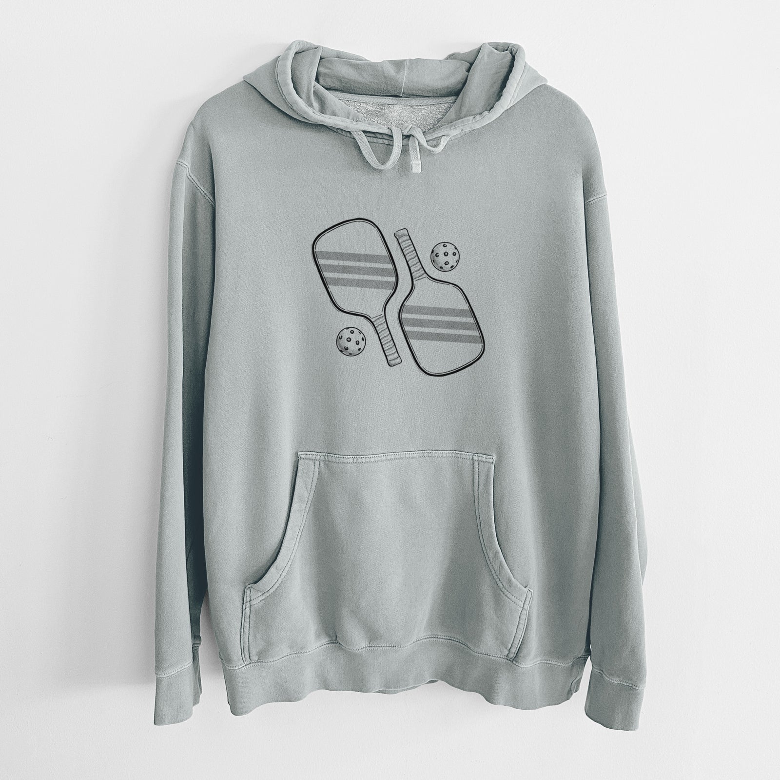 Sage green pigment dyed hoodie laid flat, printed with a black ink illustration of two crossed pickleball paddles with two pickleballs.