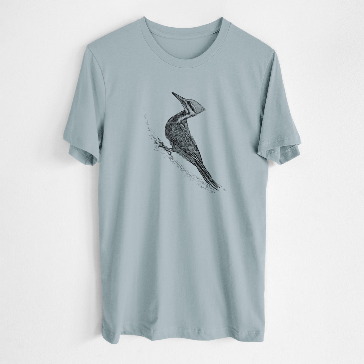 Vintage denim lightweight cotton t-shirt laid flat, printed with a black ink illustration of a pileated woodpecker clinging to a tree trunk.