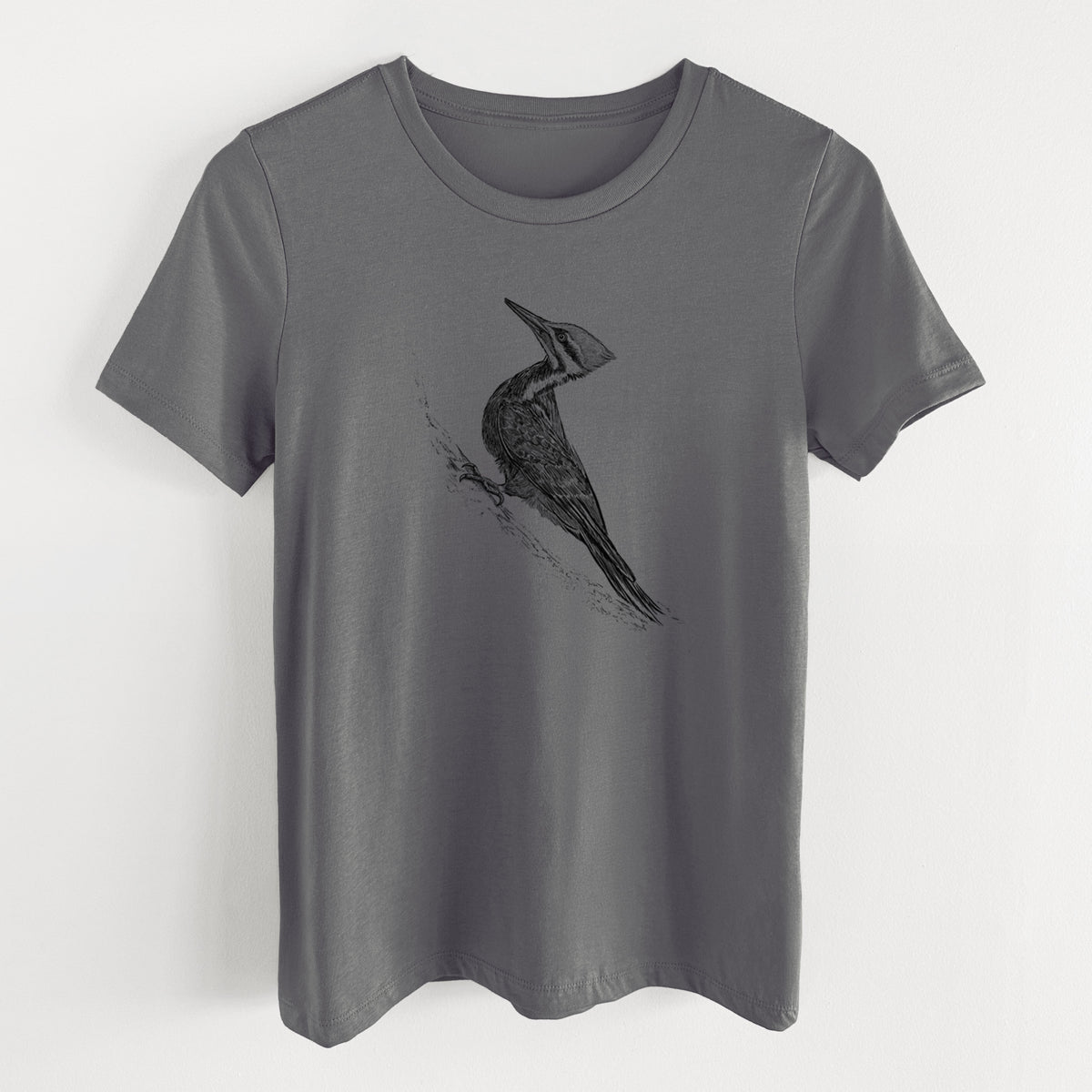 Asphalt women's relaxed fit cotton t-shirt laid flat, printed with a black ink illustration of a pileated woodpecker clinging to a tree trunk.