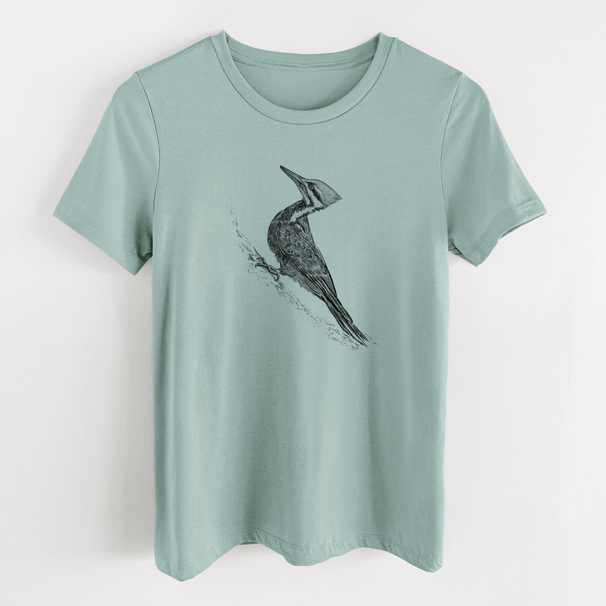 Dusty blue women's relaxed fit cotton t-shirt laid flat, printed with a black ink illustration of a pileated woodpecker clinging to a tree trunk.