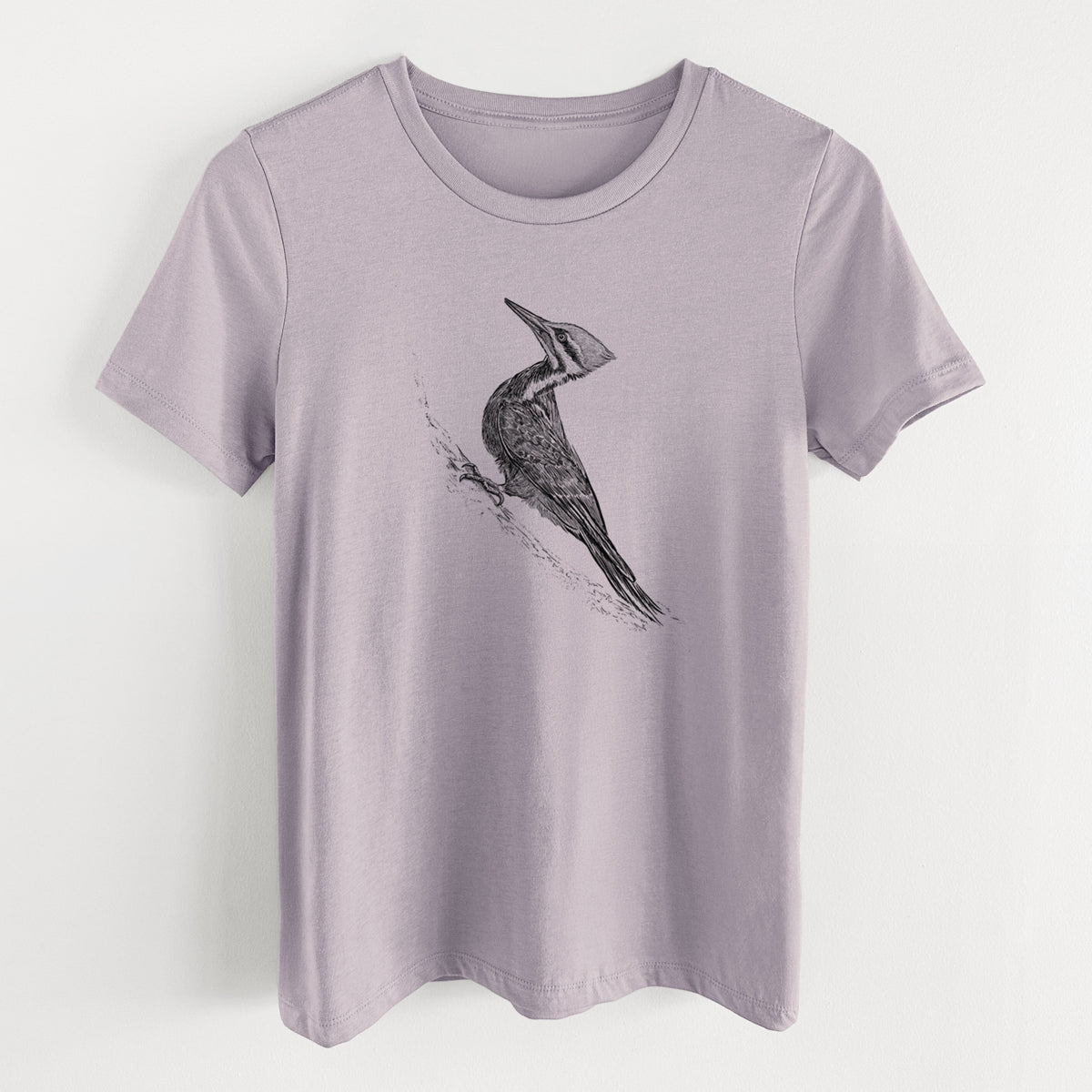 Light violet women's relaxed fit cotton t-shirt laid flat, printed with a black ink illustration of a pileated woodpecker clinging to a tree trunk.