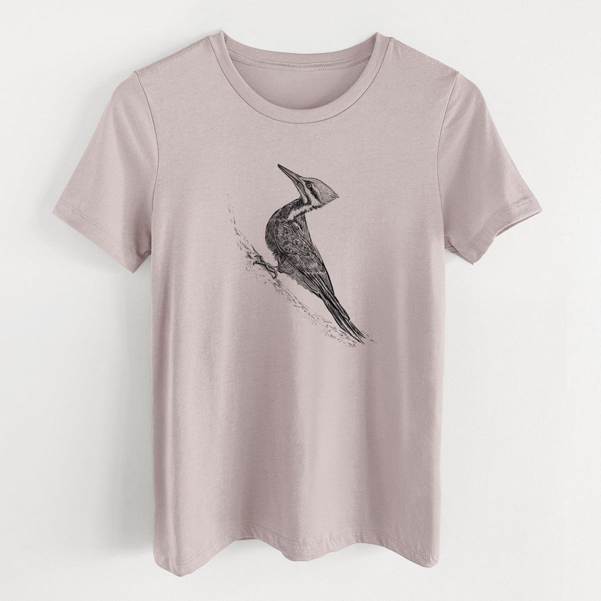 Pink gravel women's relaxed fit cotton t-shirt laid flat, printed with a black ink illustration of a pileated woodpecker clinging to a tree trunk.