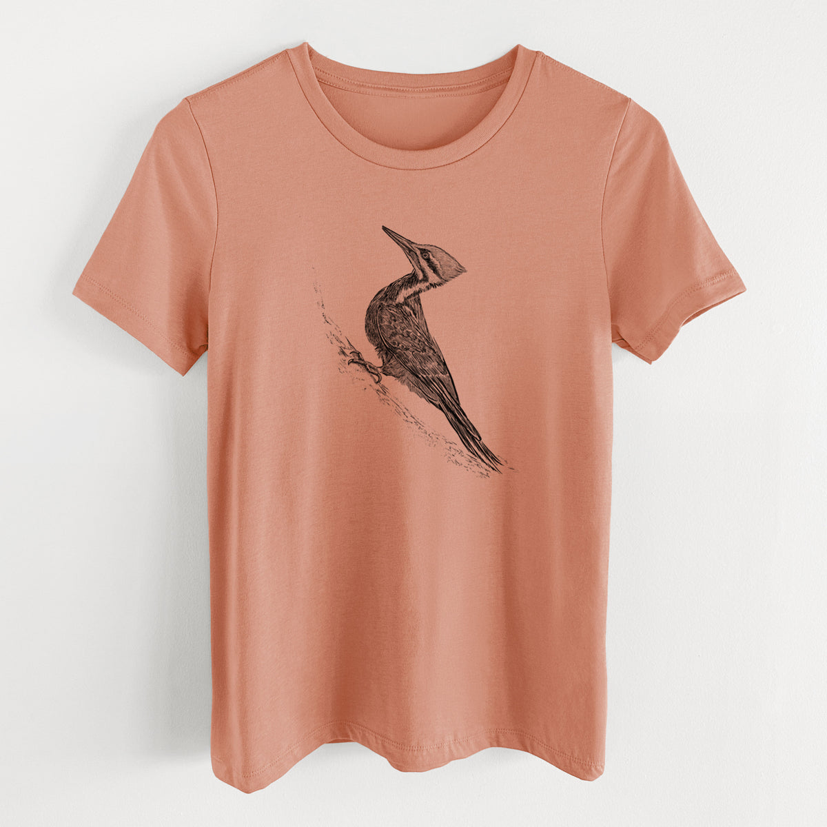 Terracotta orange women's relaxed fit cotton t-shirt laid flat, printed with a black ink illustration of a pileated woodpecker clinging to a tree trunk.
