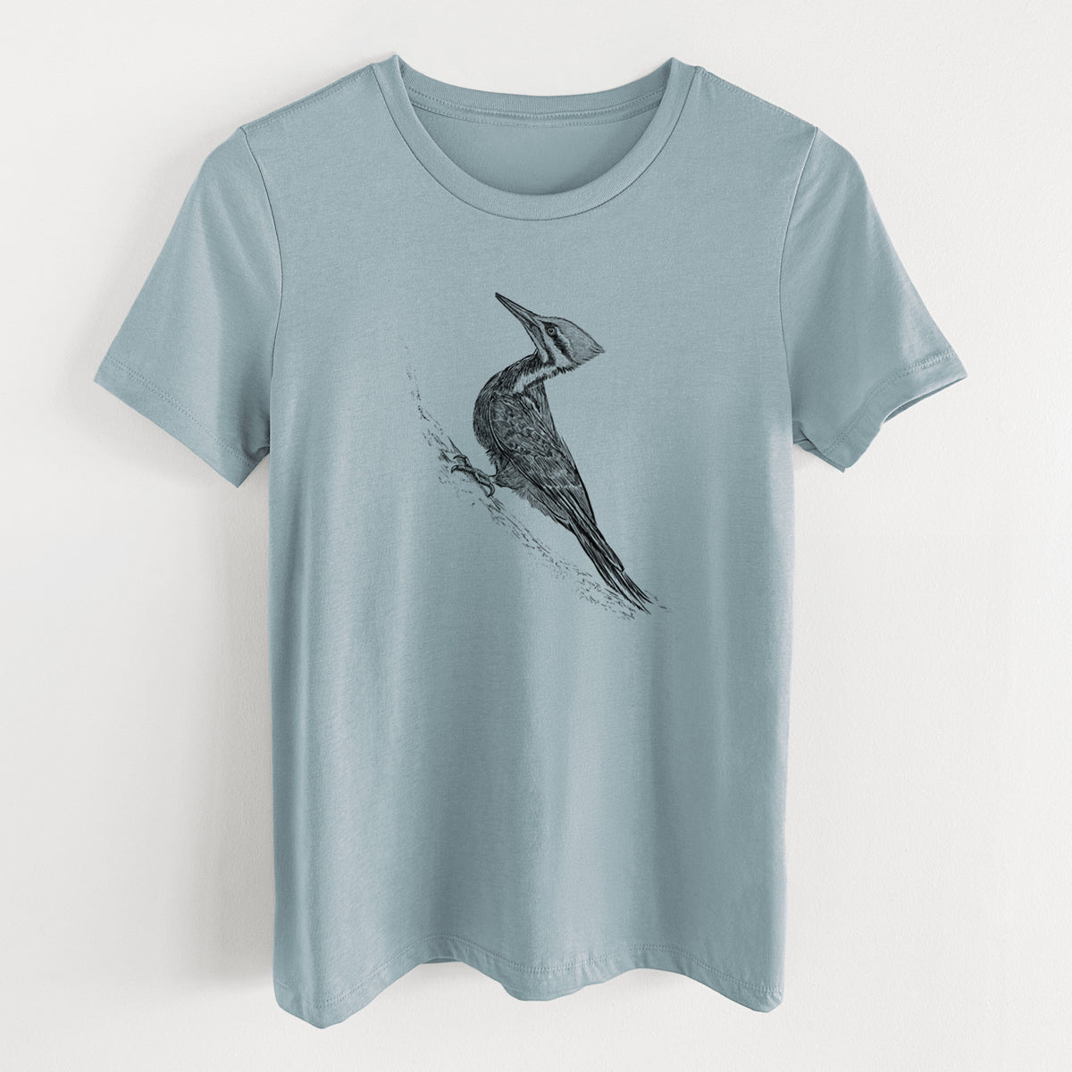 Vintage denim women's relaxed fit cotton t-shirt laid flat, printed with a black ink illustration of a pileated woodpecker clinging to a tree trunk.