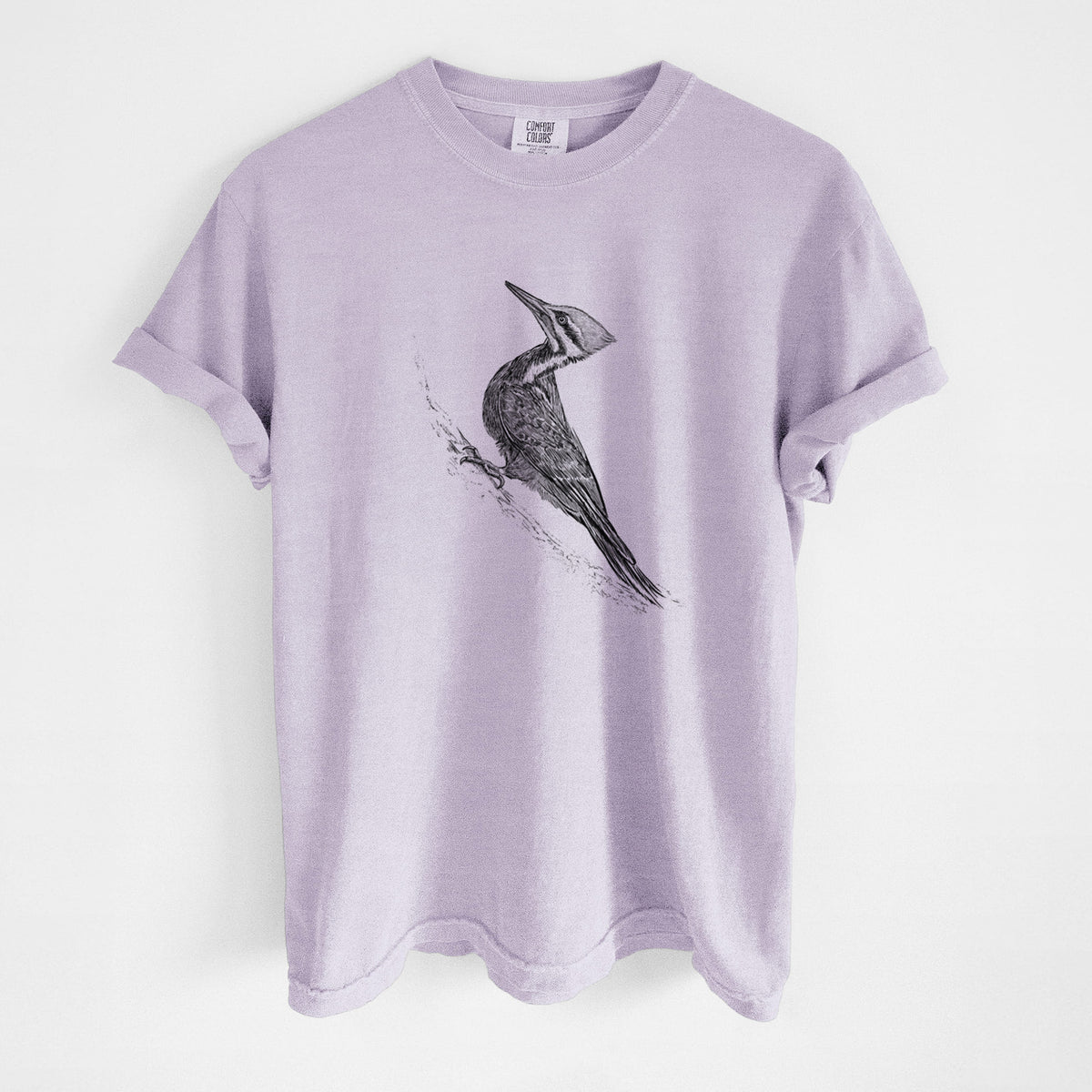Orchid purple Comfort Colors t-shirt laid flat, printed with a black ink illustration of a pileated woodpecker clinging to a tree trunk.