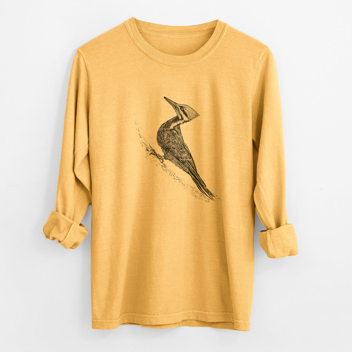 Golden wheat yellow Comfort Colors long sleeve shirt laid flat with the cuffs rolled, printed with a black ink illustration of a pileated woodpecker clinging to a tree trunk.