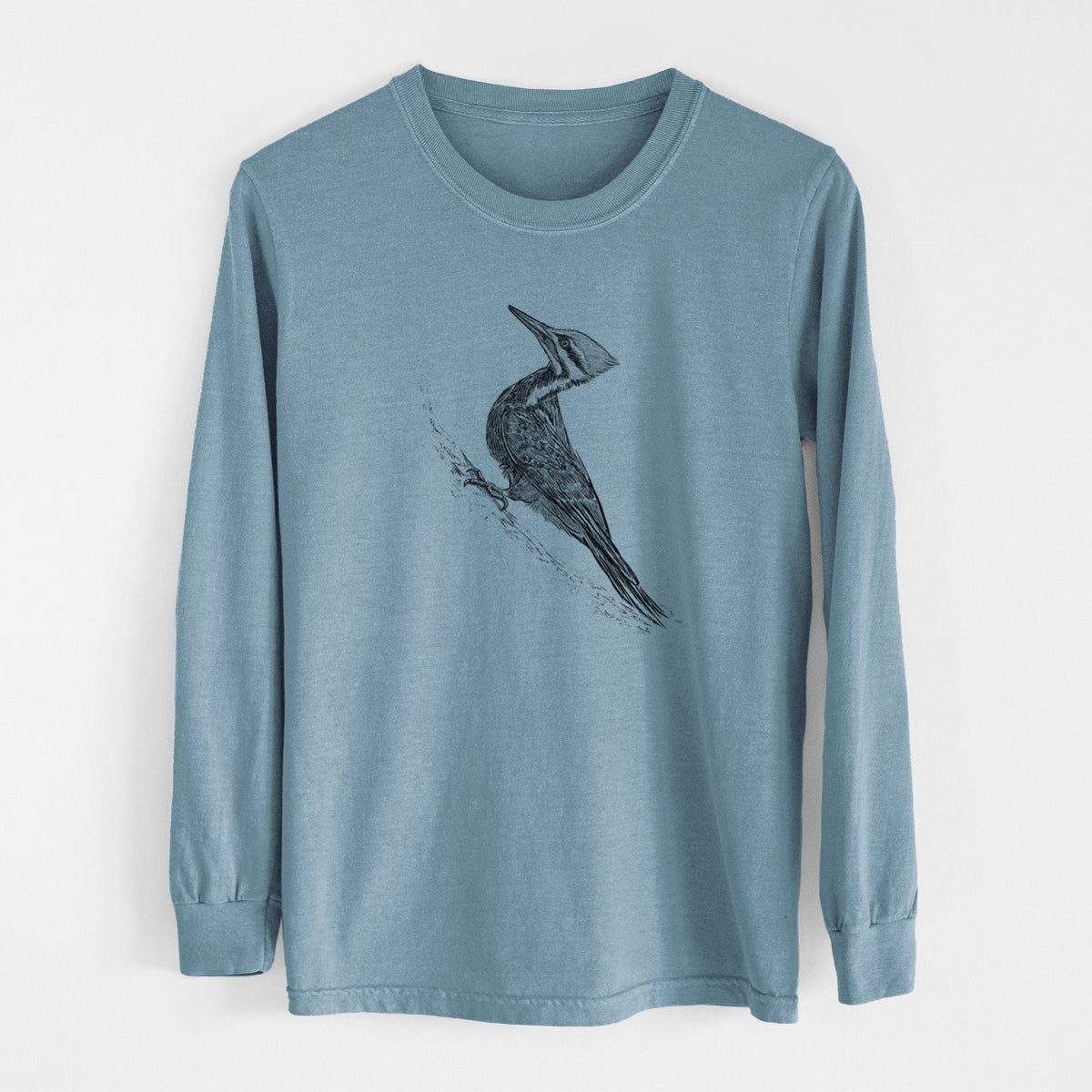 Steel blue Comfort Colors long sleeve shirt laid flat, printed with a black ink illustration of a pileated woodpecker clinging to a tree trunk.