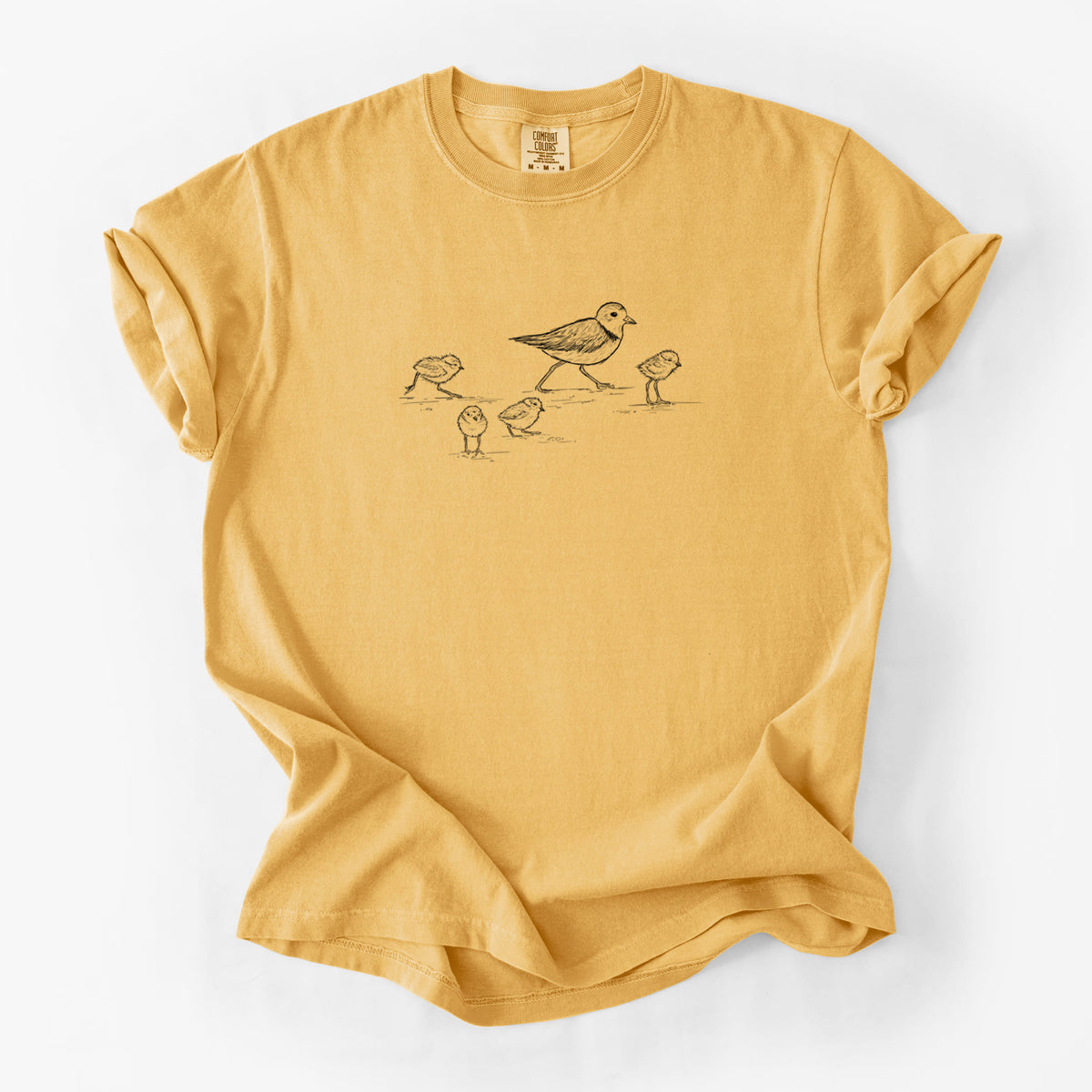 Golden wheat yellow Comfort Colors t-shirt laid flat, printed with a black ink sketch of a piping plover with its chicks on the sand.