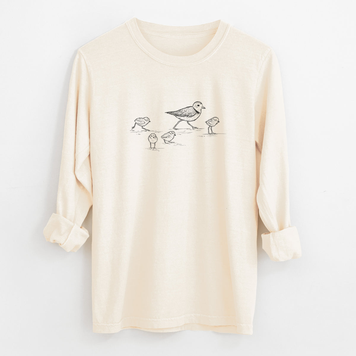 Ivory Comfort Colors long sleeve shirt laid flat with the cuffs rolled, printed with a black ink sketch of a piping plover with its chicks on the sand.