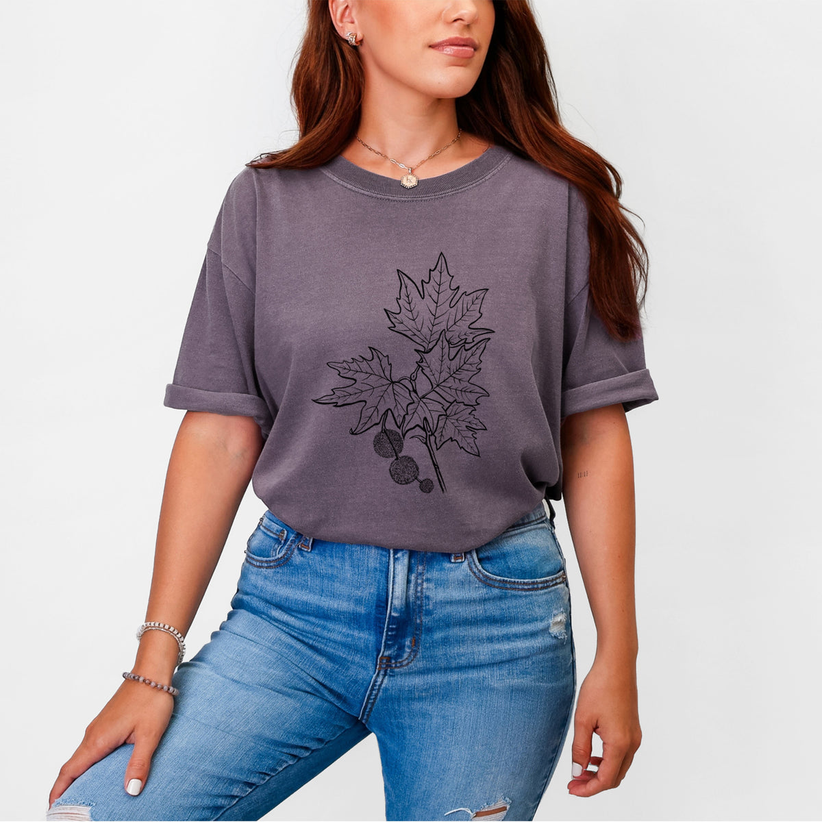 Woman wearing a Comfort Colors t-shirt printed with a black ink illustration of an oriental plane tree branch with lobed leaves and round seed balls.