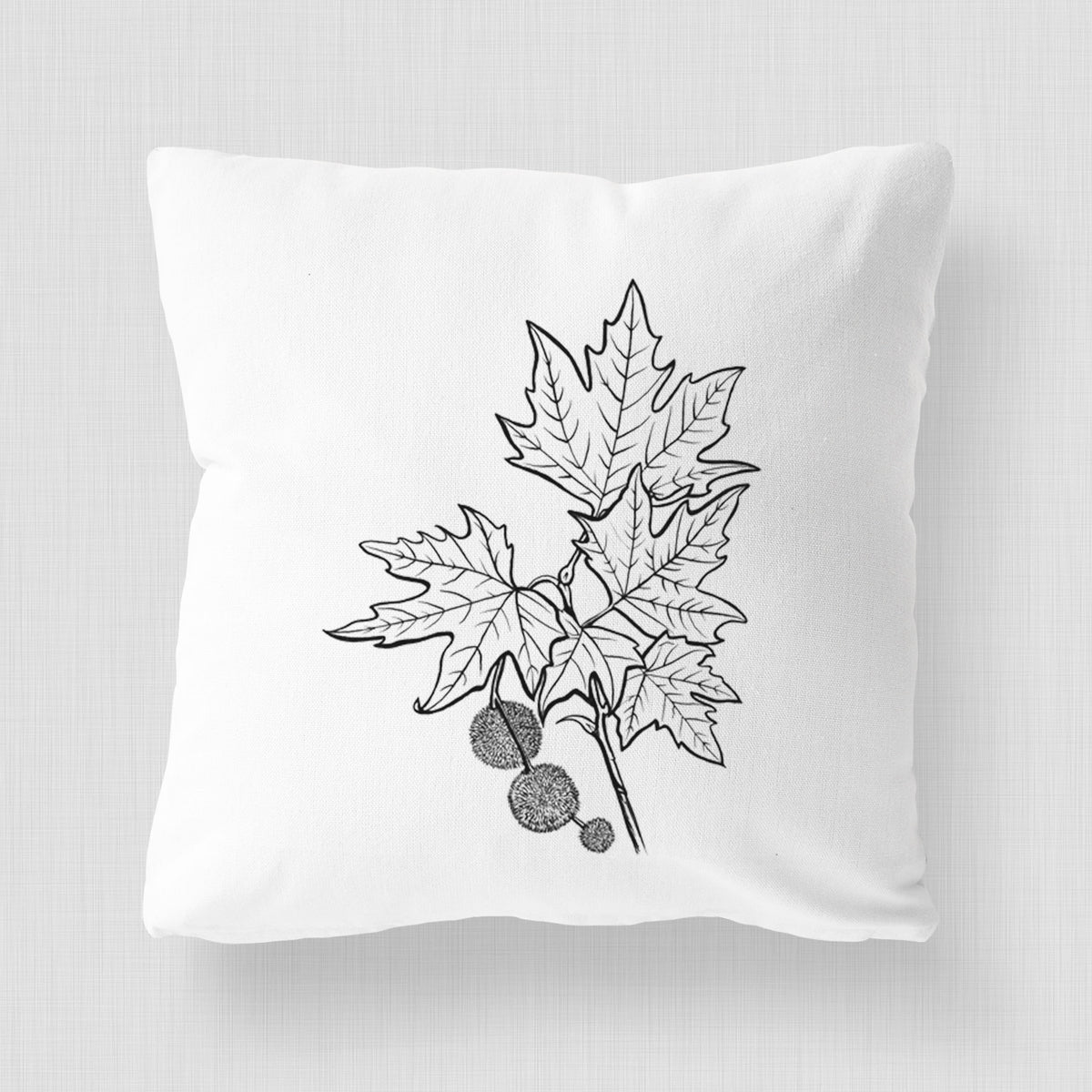 White pillow cover printed with a black ink illustration of an oriental plane tree branch with lobed leaves and round seed balls.