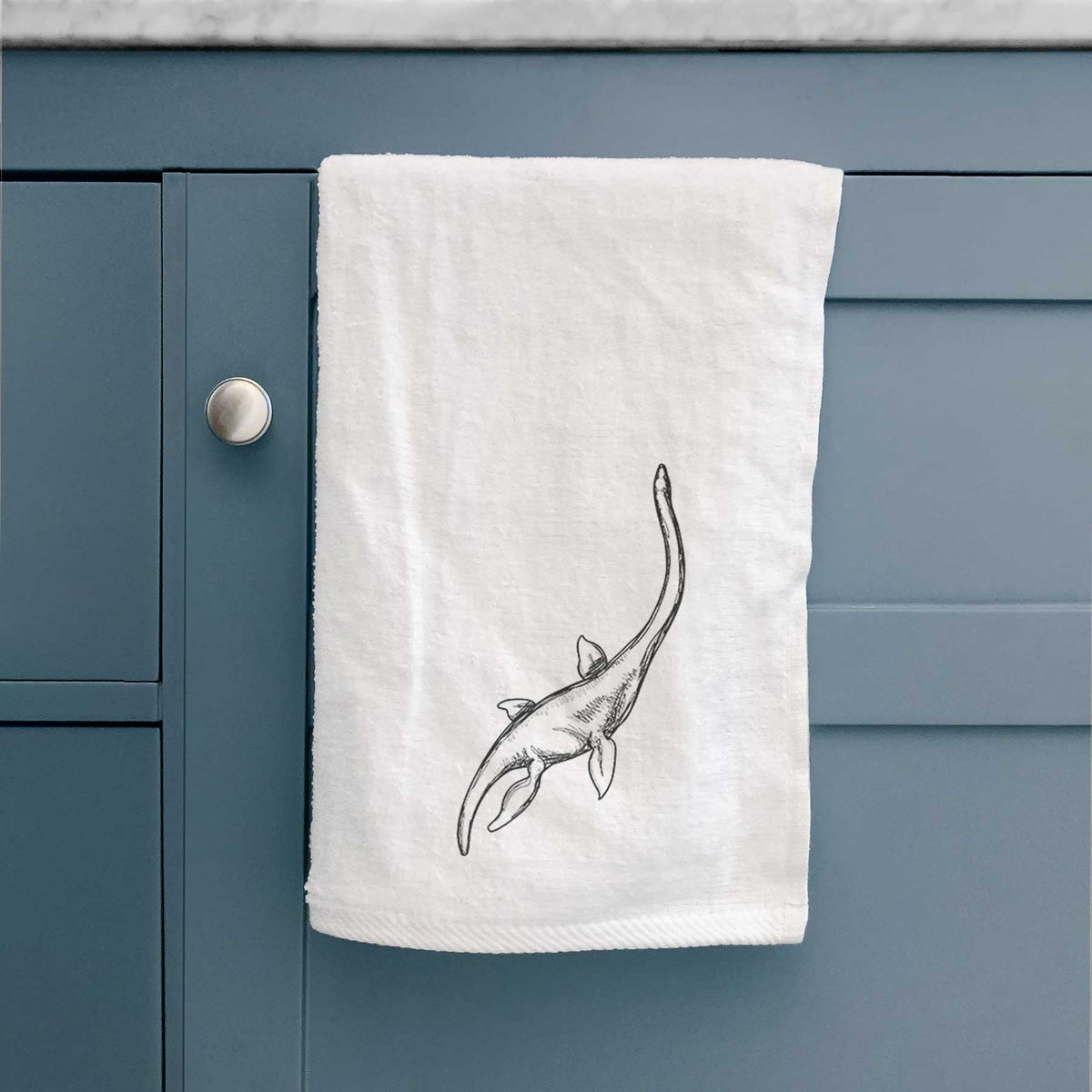 White hand towel printed with a black ink illustration of a long-necked plesiosaur swimming.