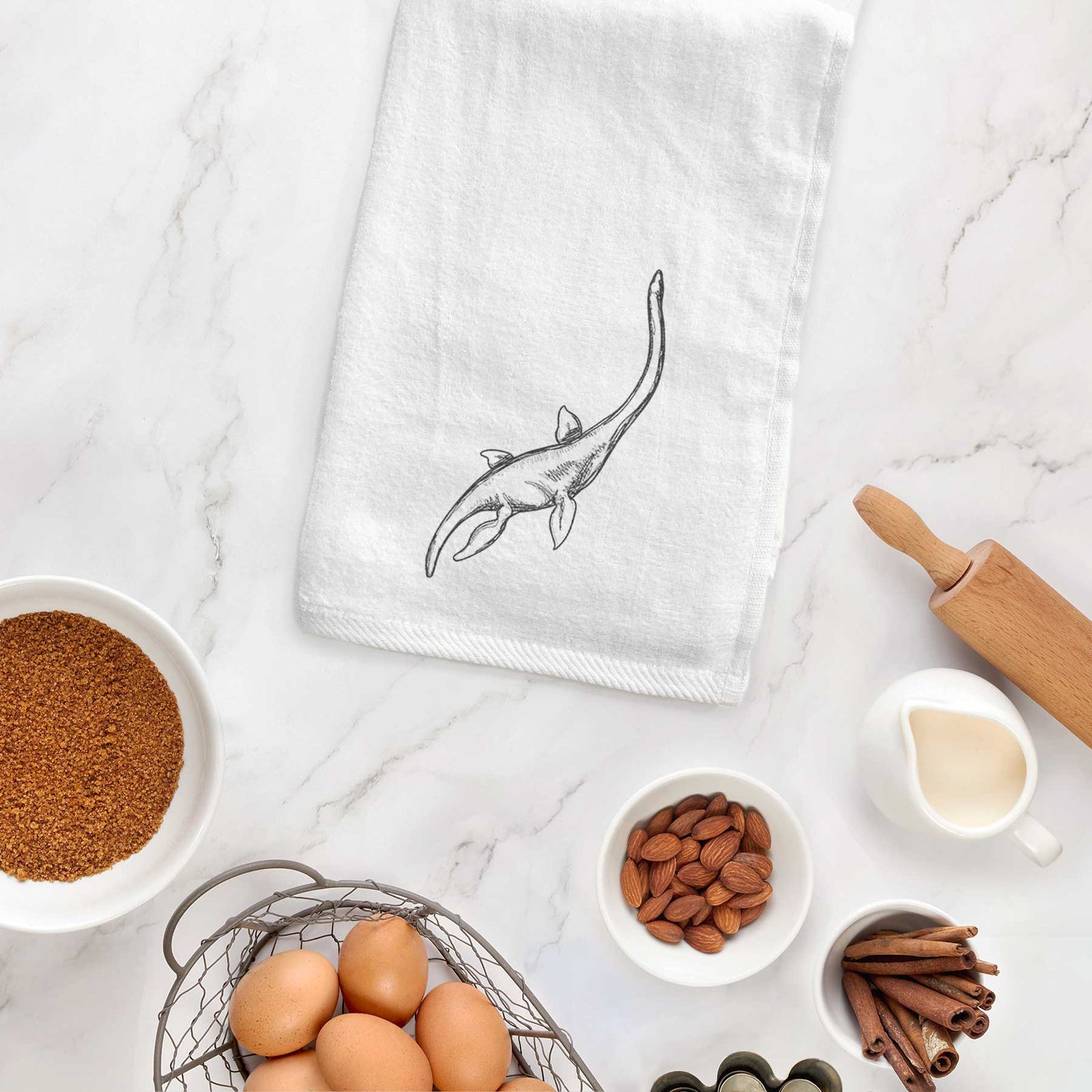 White hand towel printed with a black ink illustration of a long-necked plesiosaur swimming.