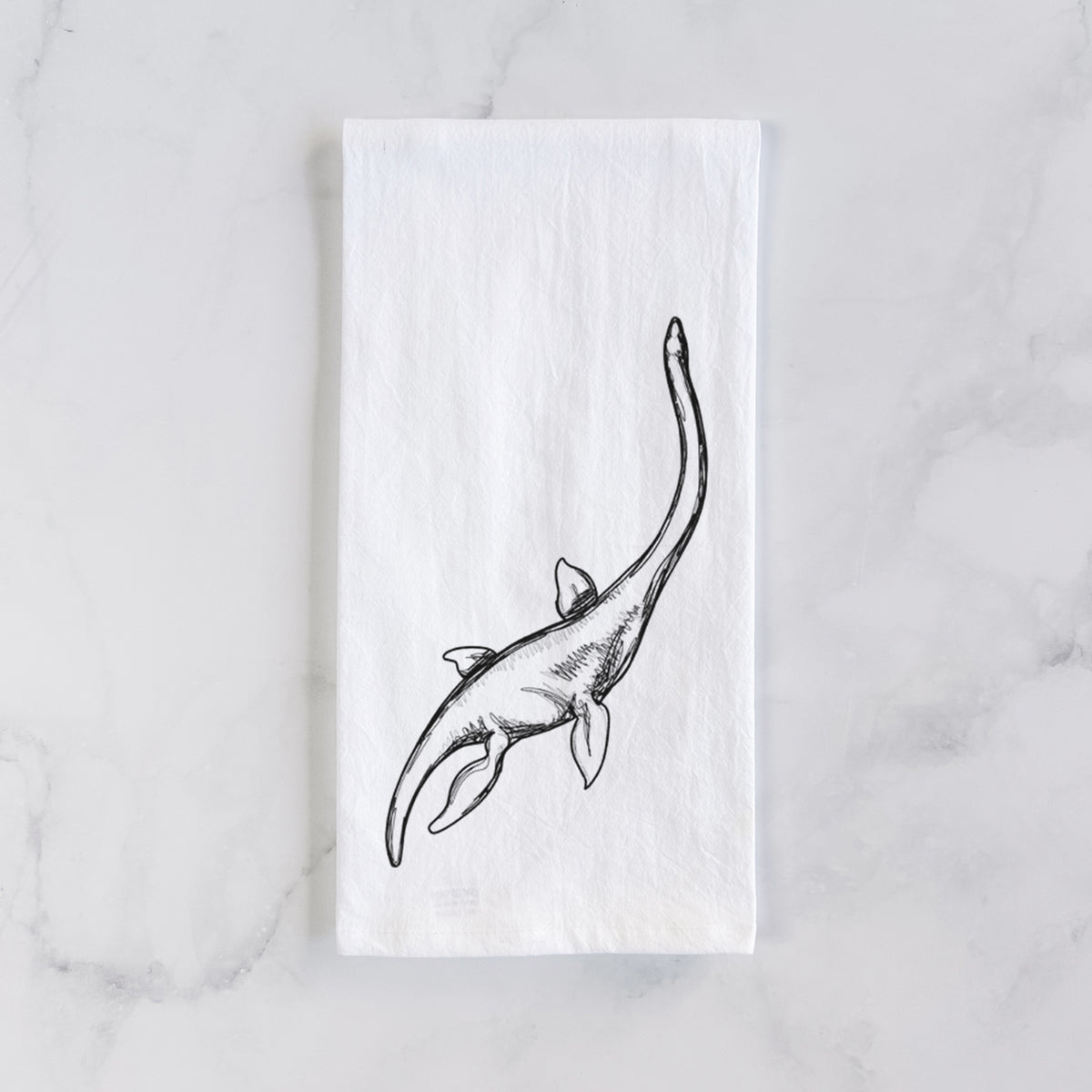 White cotton tea towel laid flat on marble, printed with a black ink illustration of a long-necked plesiosaur swimming.