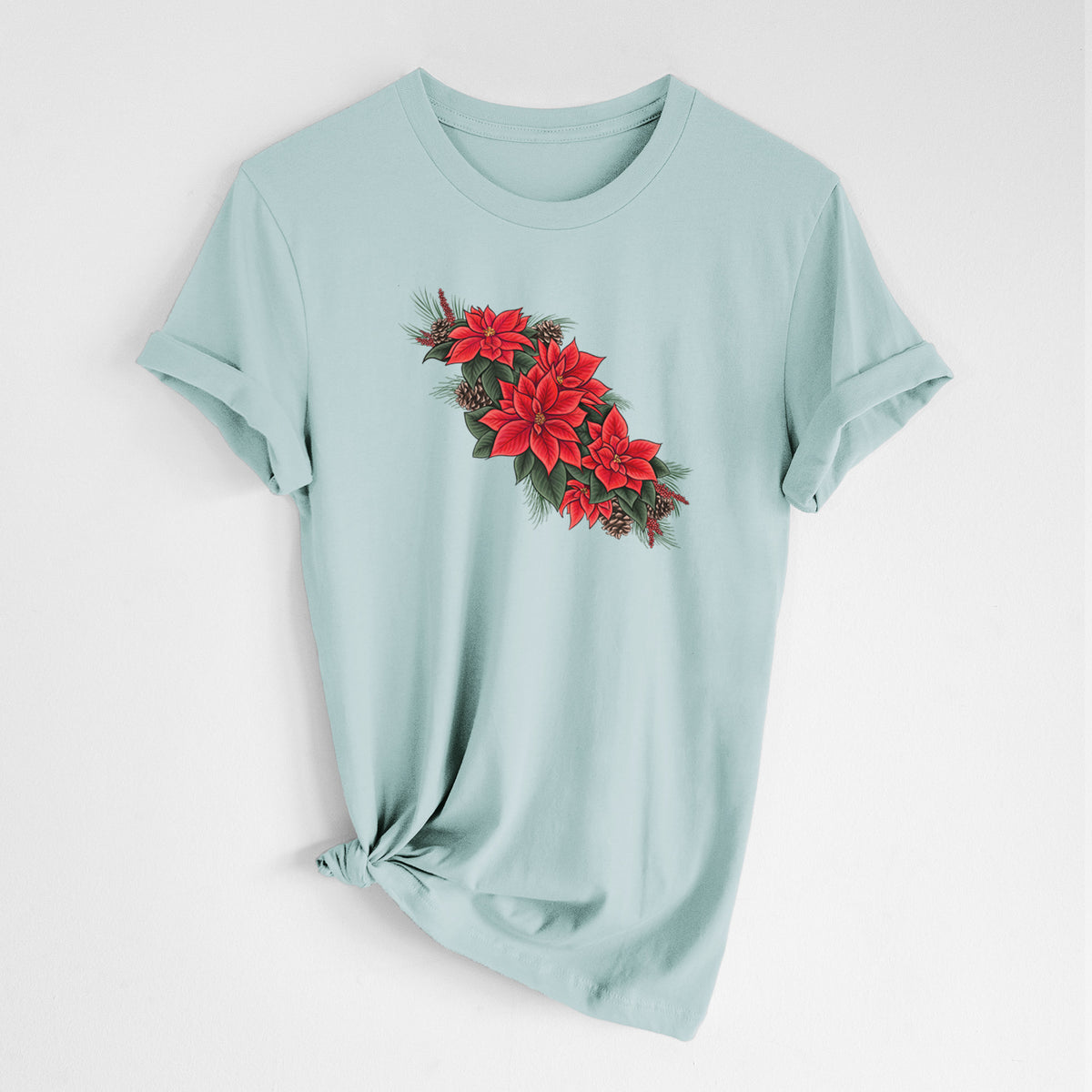 Dusty blue lightweight cotton t-shirt laid flat with the sleeves rolled, printed with a full-color illustration of red poinsettia flowers with pine greenery and pine cones.