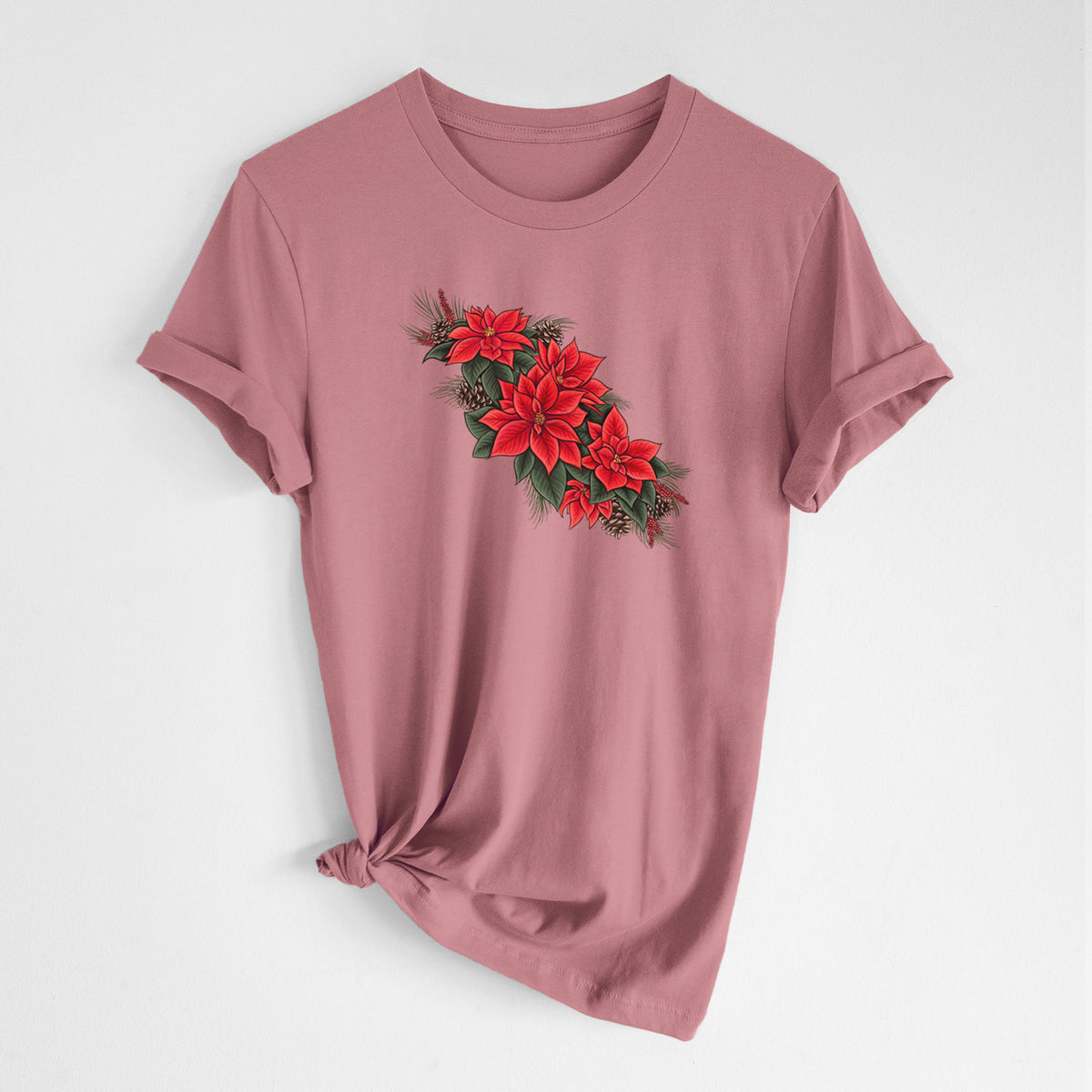 Mauve pink lightweight cotton t-shirt laid flat with the sleeves rolled, printed with a full-color illustration of red poinsettia flowers with pine greenery and pine cones.