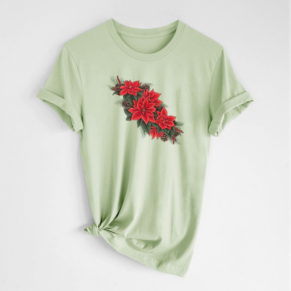 Spring green lightweight cotton t-shirt laid flat with the sleeves rolled, printed with a full-color illustration of red poinsettia flowers with pine greenery and pine cones.