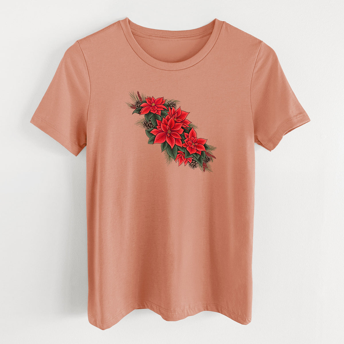 Terracotta orange women's relaxed fit cotton t-shirt laid flat, printed with a full-color illustration of red poinsettia flowers with pine greenery and pine cones.