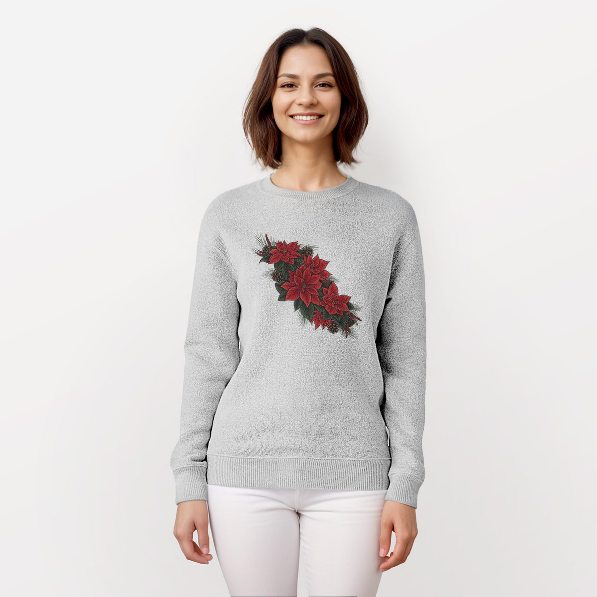 Woman wearing a knit sweatshirt printed with a full-color illustration of red poinsettia flowers with pine greenery and pine cones.